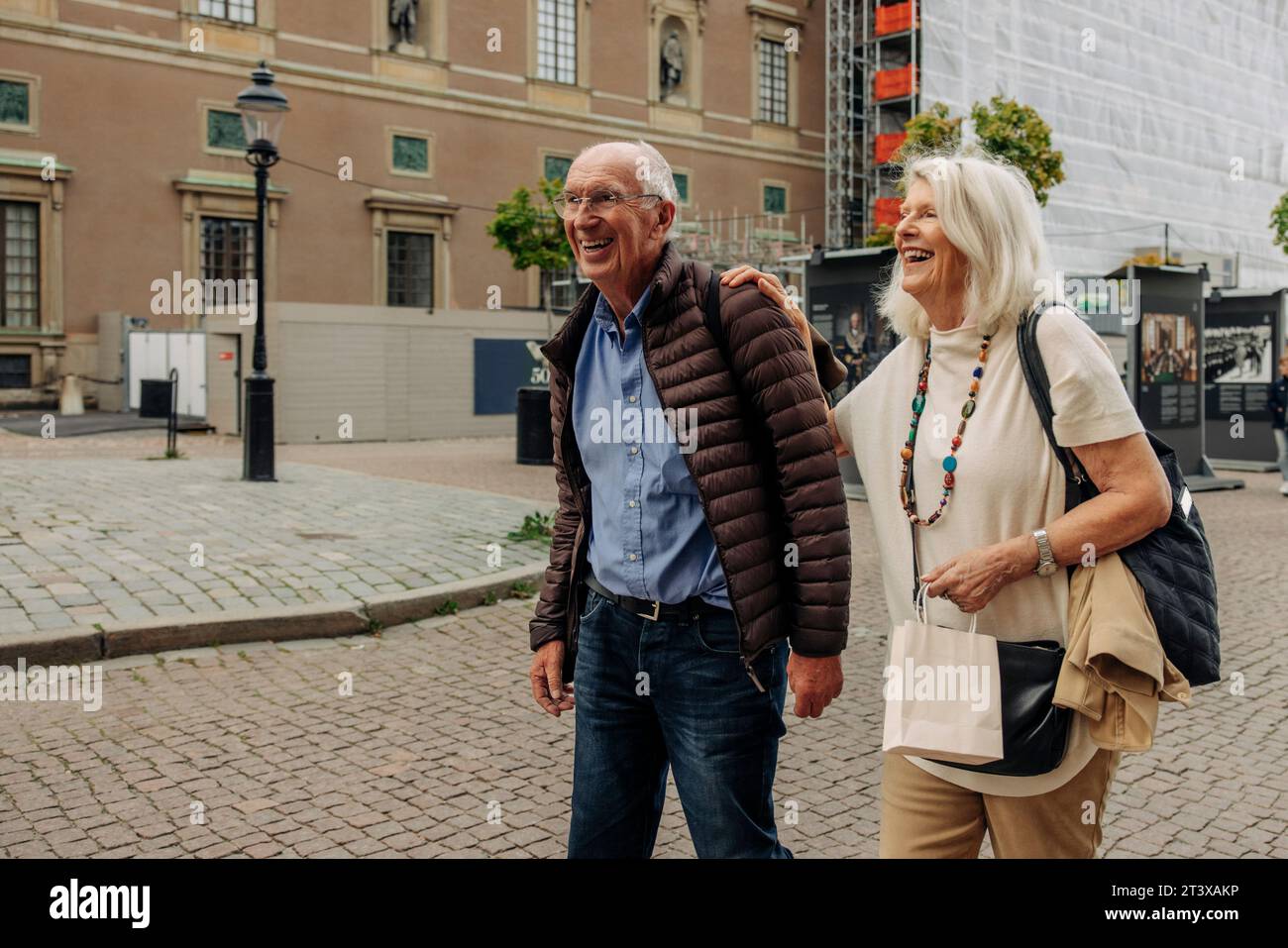 Felice coppia anziana in pensione che cammina per strada in città Foto Stock