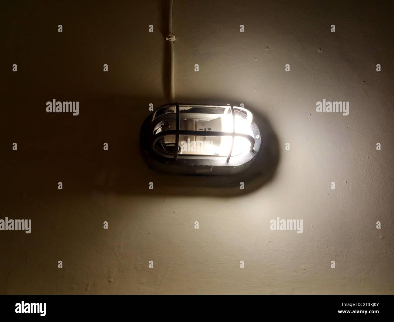 Corridoio sotterraneo con pareti in cemento e illuminato da vecchie lampade. Foto Stock