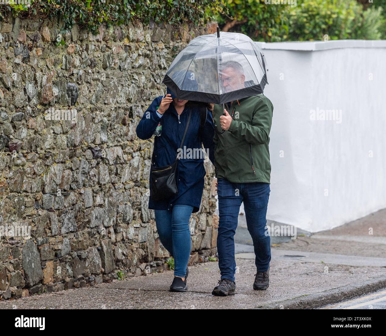 Persone che lottano contro i venti forti e la pioggia forte sotto un Met Éireann Weather Warning a Tramore, Co. Waterford, Irlanda. Foto Stock