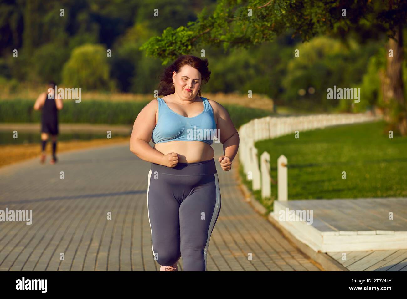 Donna caucasica in sovrappeso che fa sport e corre al mattino nel parco. Foto Stock