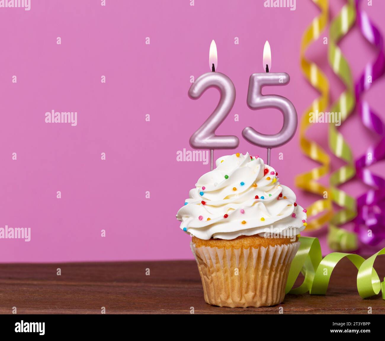 Torta di compleanno con candela numero 25 - su sfondo rosa. Foto Stock