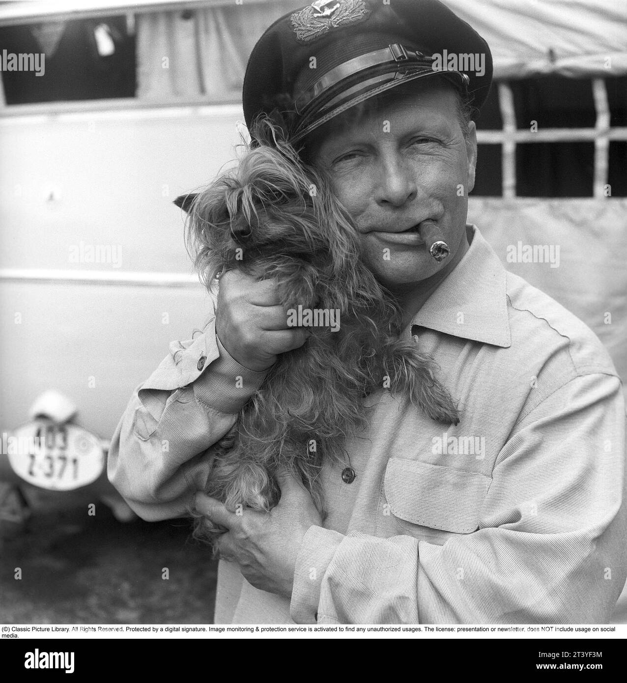 Negli anni '1950 Un uomo immaginato insieme al suo piccolo cane che gli piace visibilmente e tiene vicino. Sta fumando un sigaro e indossa un berretto. Svezia 1951. Kristoffersson rif. BP31-2 Foto Stock