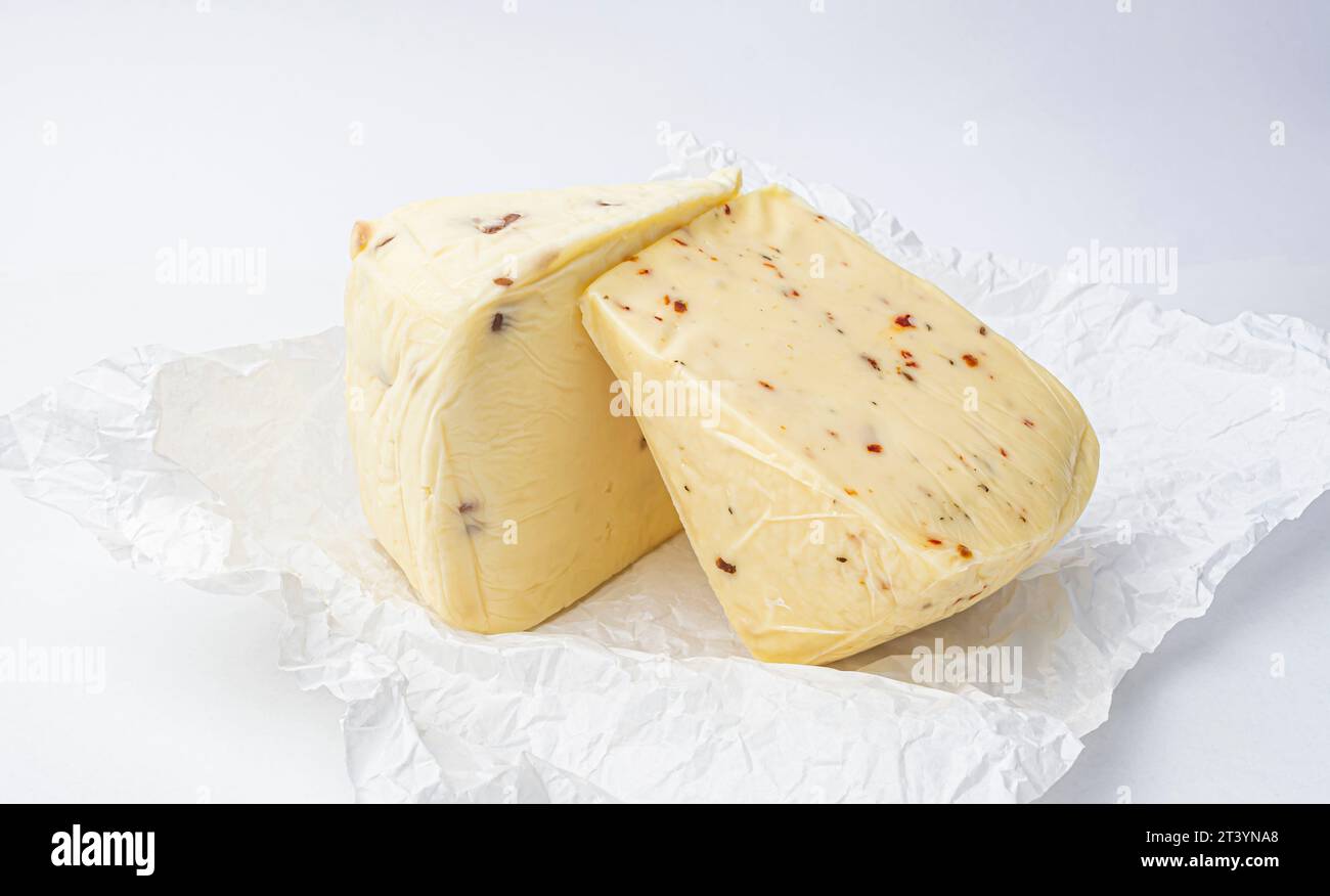 pezzo di formaggio con noci e paprika su carta di menta bianca da vicino Foto Stock