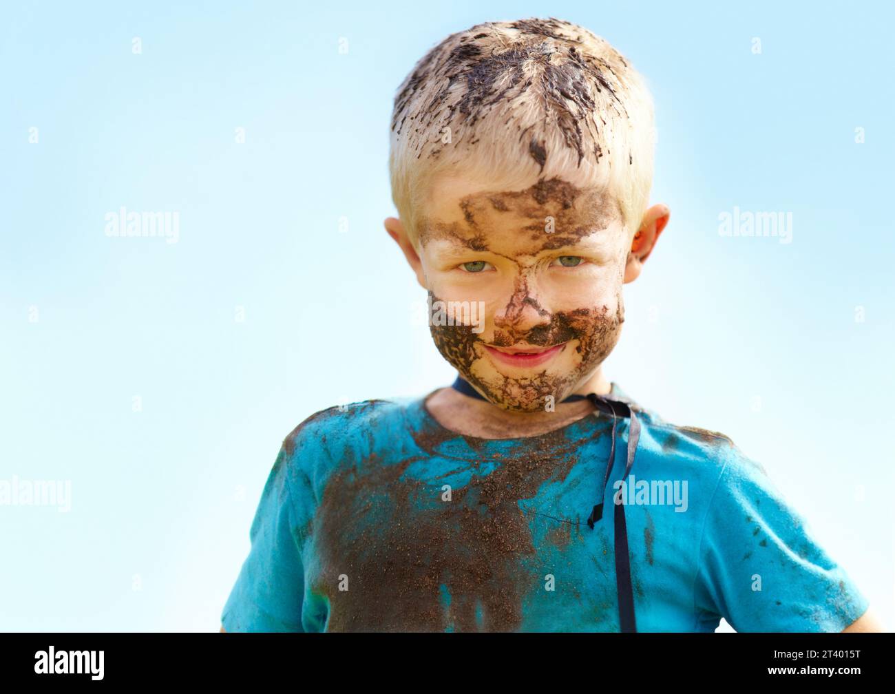 Ragazzo, bambino e fango sul viso con il sorriso del gioco, sporco o felicità in estate o in acqua. Bambino, persona e ritratto con soddisfazione per il disordine Foto Stock