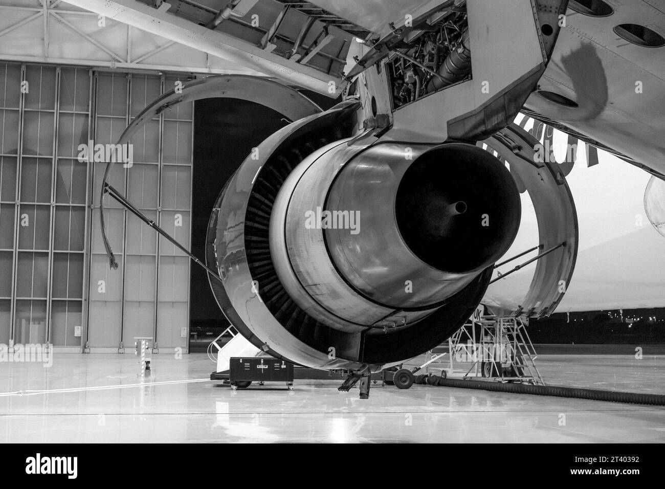 Riparazione aereo nell'hangar. Motore aereo sull'ala. Manutenzione. Foto in bianco e nero. Foto Stock