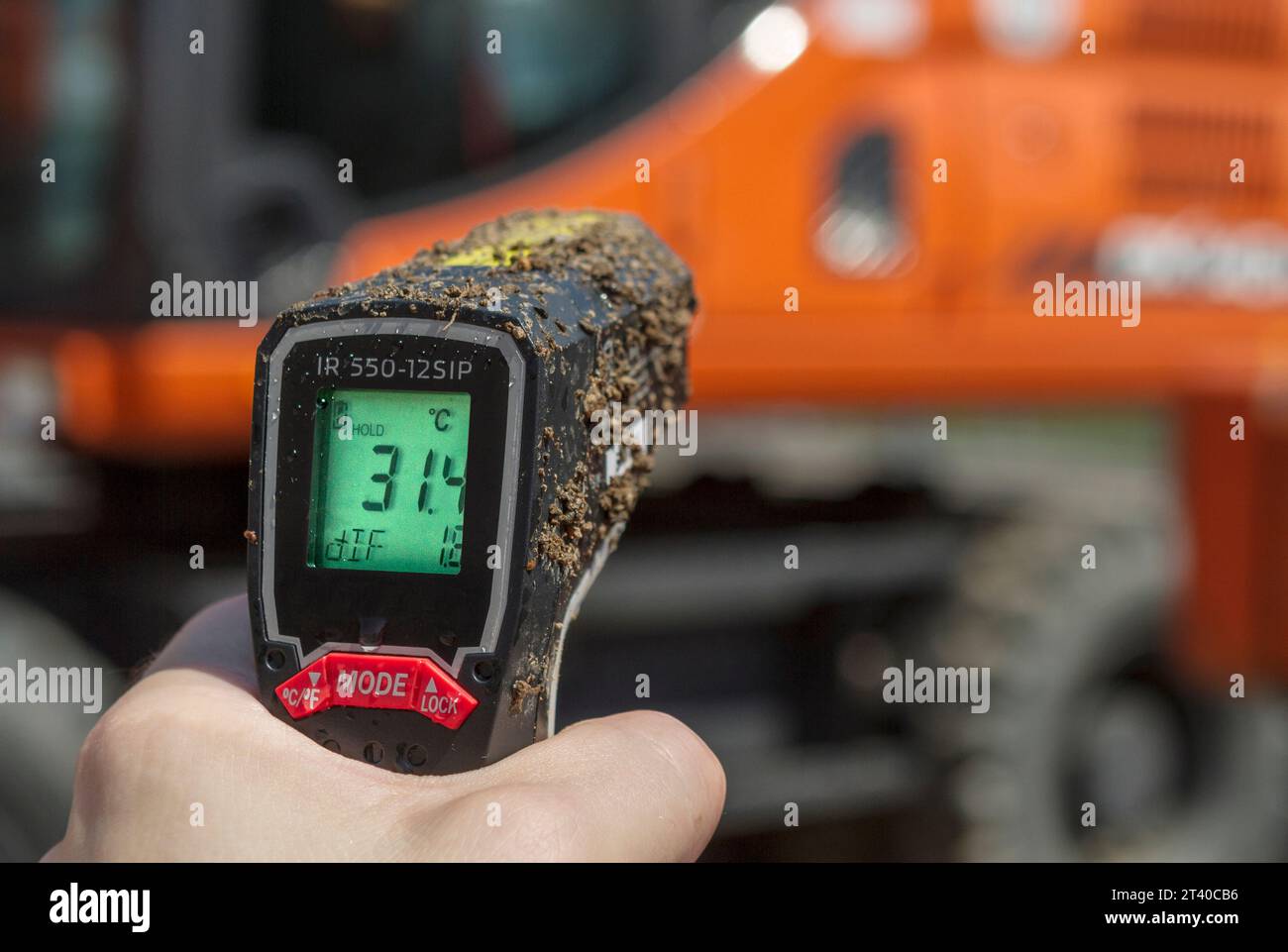 Misurazione della temperatura del motore su un veicolo da cantiere con un termometro digitale a infrarossi Foto Stock