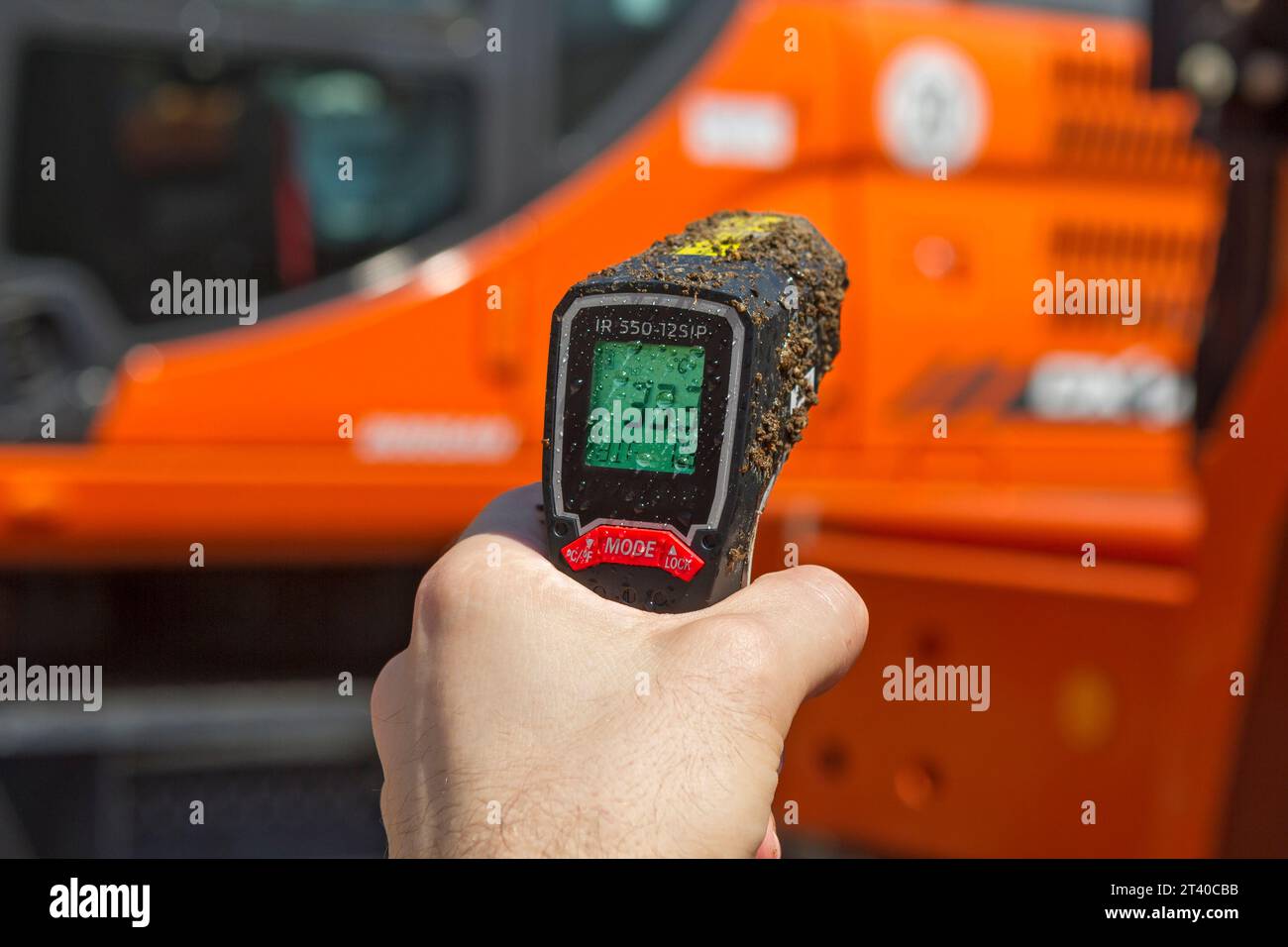 Misurazione della temperatura del motore su un veicolo da cantiere con un termometro digitale a infrarossi Foto Stock