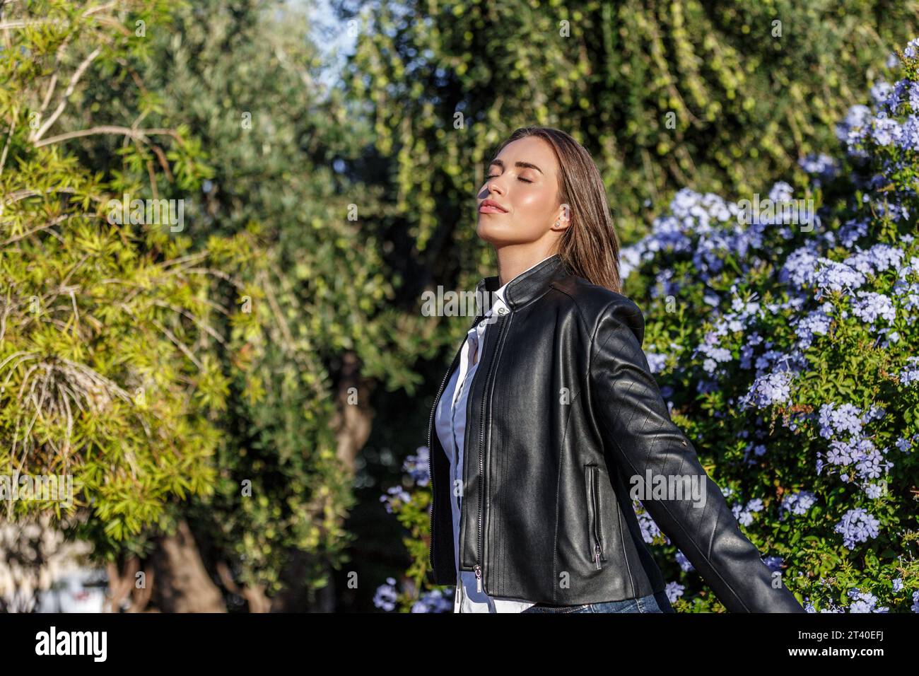 Giovane donna con gli occhi chiusi 20 anni caucasica sola nel parco respirando aria fresca in una giornata di sole Foto Stock