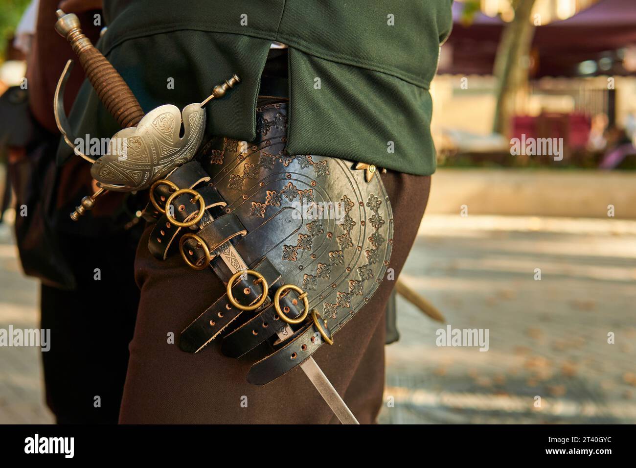 Vecchia spada da soldato su un costume medievale da cavaliere. Rievocazione storica di un'arma. Foto Stock