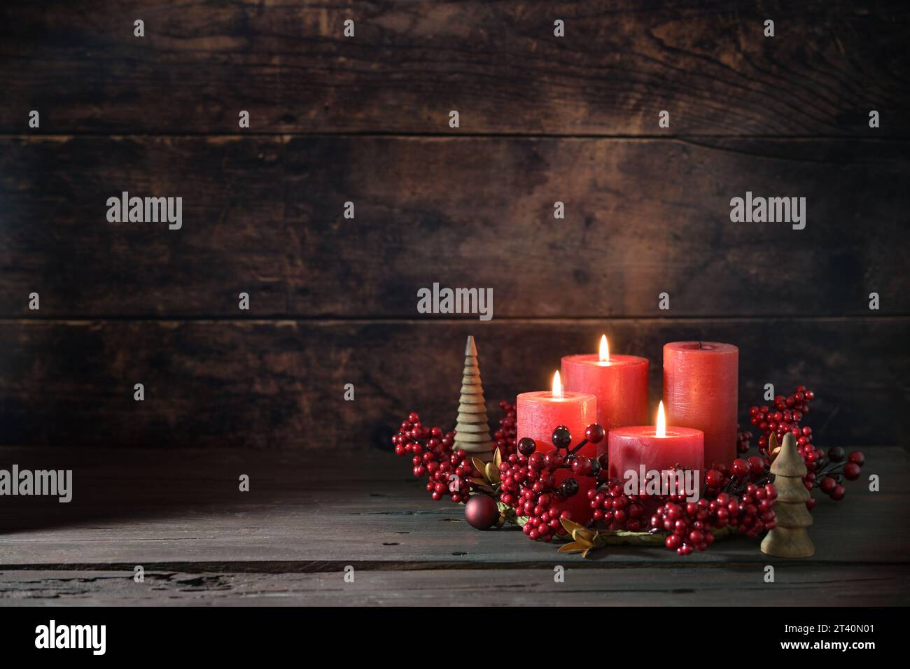 Terza corona dell'avvento con candele rosse, tre sono accese, decorazione con frutti di bosco, palle di Natale e piccoli alberi di legno, sfondo rustico scuro, copia spa Foto Stock