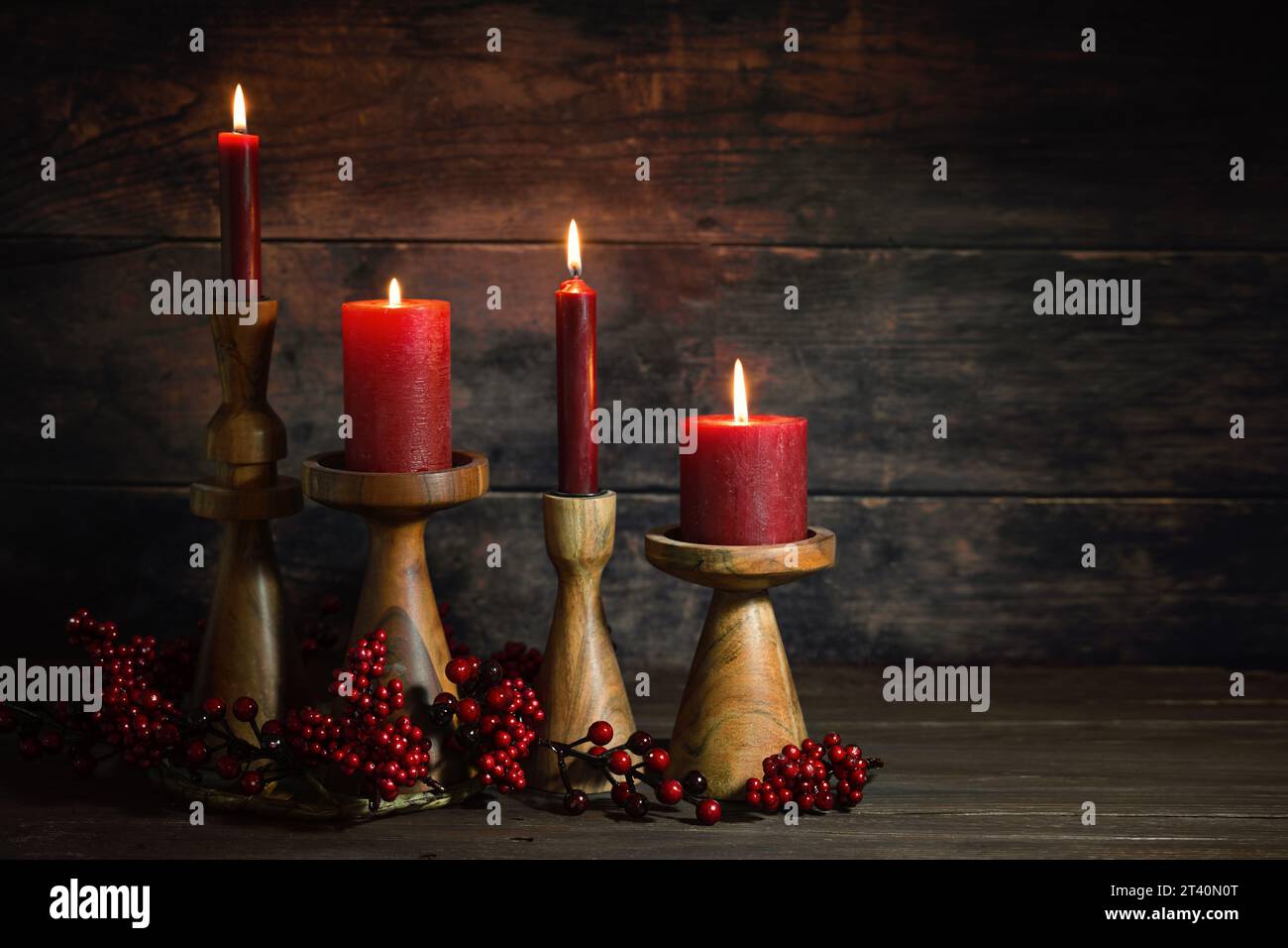 Quattro candele rosse in candelabri di legno di fila come decorazione dell'Avvento o del Natale su uno sfondo rustico scuro, decorazioni naturali per la casa delle vacanze, copia Foto Stock