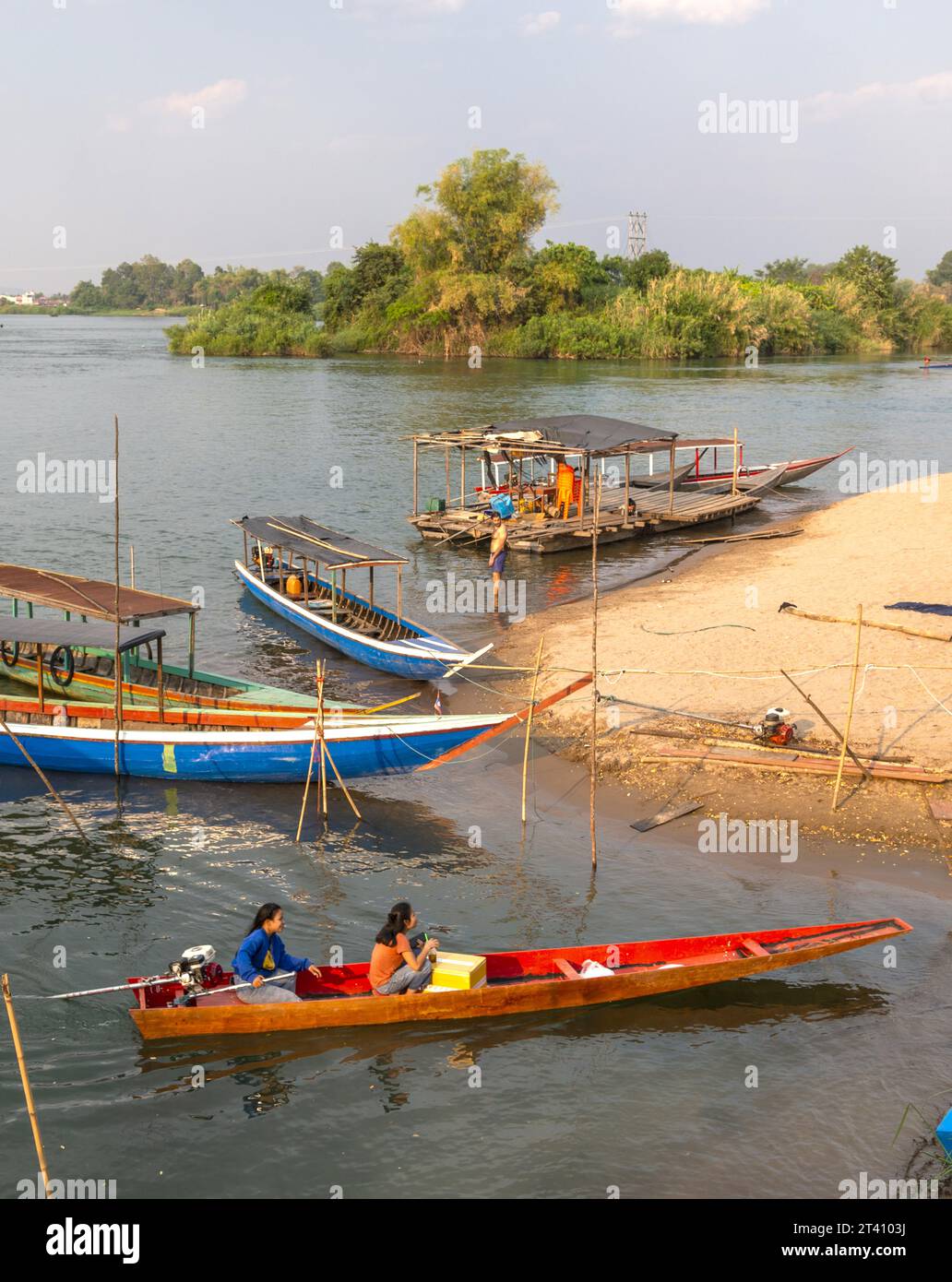,4000 Islands, si Phan Don, Khong District, Laos-21 febbraio 2023: I viaggiatori si ritrovano e escono dalla piccola spiaggia del fiume Mekong, dove fanno capolino i piccoli traghetti Foto Stock