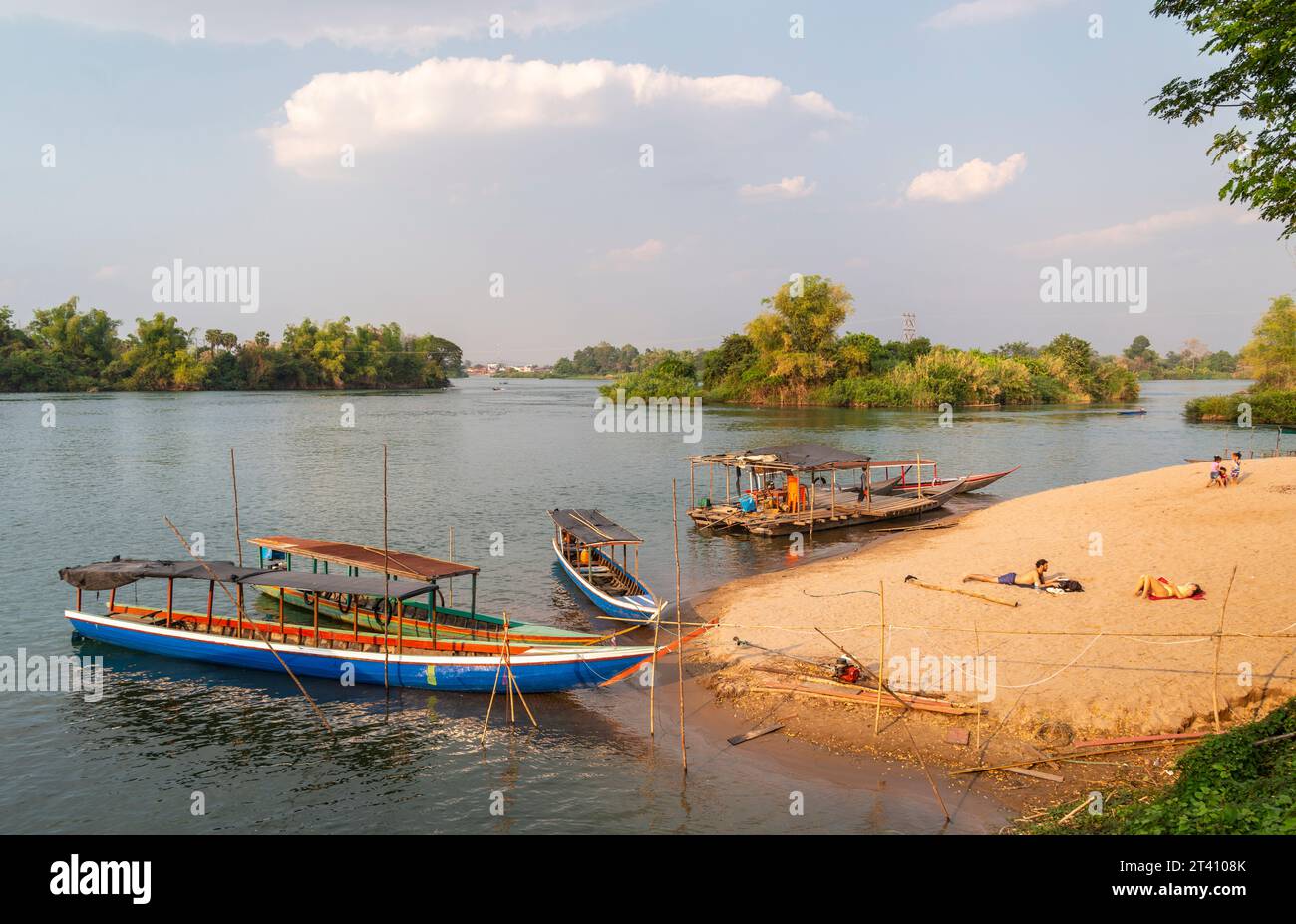 ,4000 isole, si Phan Don, Khong District, Laos-21 febbraio 2023: I viaggiatori si rilassano sulla piccola spiaggia del fiume Mekong, piccole barche di legno che portano a An Foto Stock