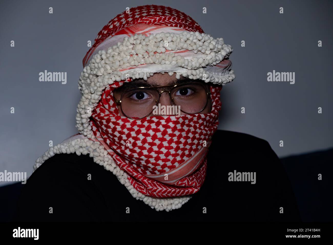 ritratto di pearson che indossa keffiyeh rosso su sfondo scuro con espressione di rabbia sugli occhi a causa della violenza e contro l'occupazione Foto Stock