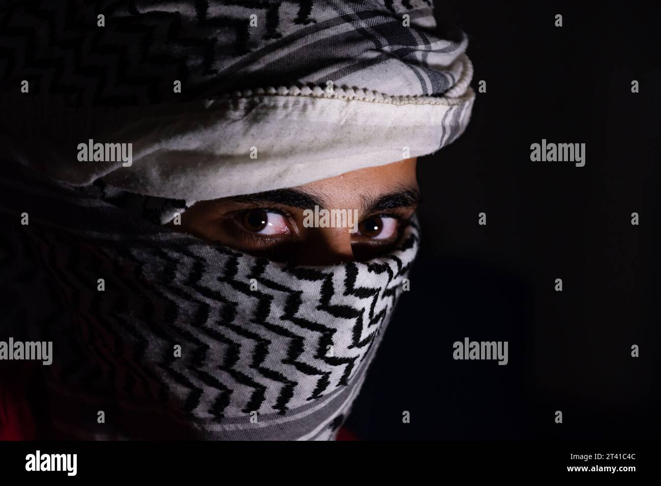 ritratto di pearson che indossa keffiyeh bianco su sfondo scuro con espressione di rabbia sugli occhi a causa della violenza e contro l'occupazione Foto Stock