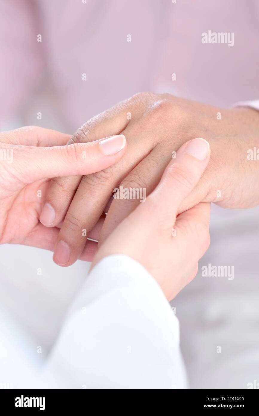 Il medico controlla la mano dell'uomo Foto Stock