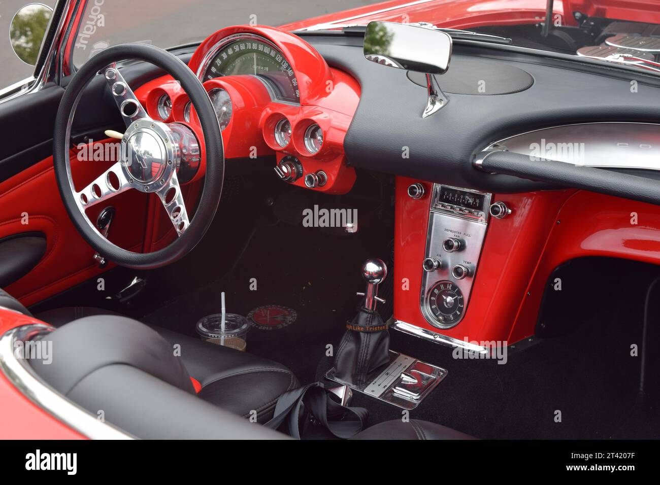 Un cruscotto rosso d'epoca Corvette Convertible Sports con volante nero, visto da un cofano inclinato in alto in occasione del salone di auto d'epoca Foto Stock