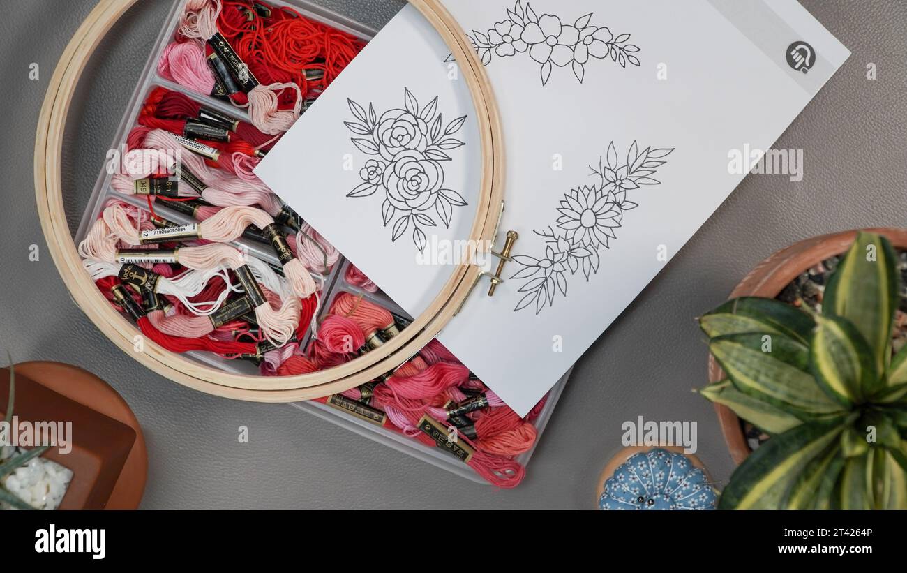 Motivi floreali ricamati a mano su un foglio da cucire su un cavalletto di legno. Foto Stock