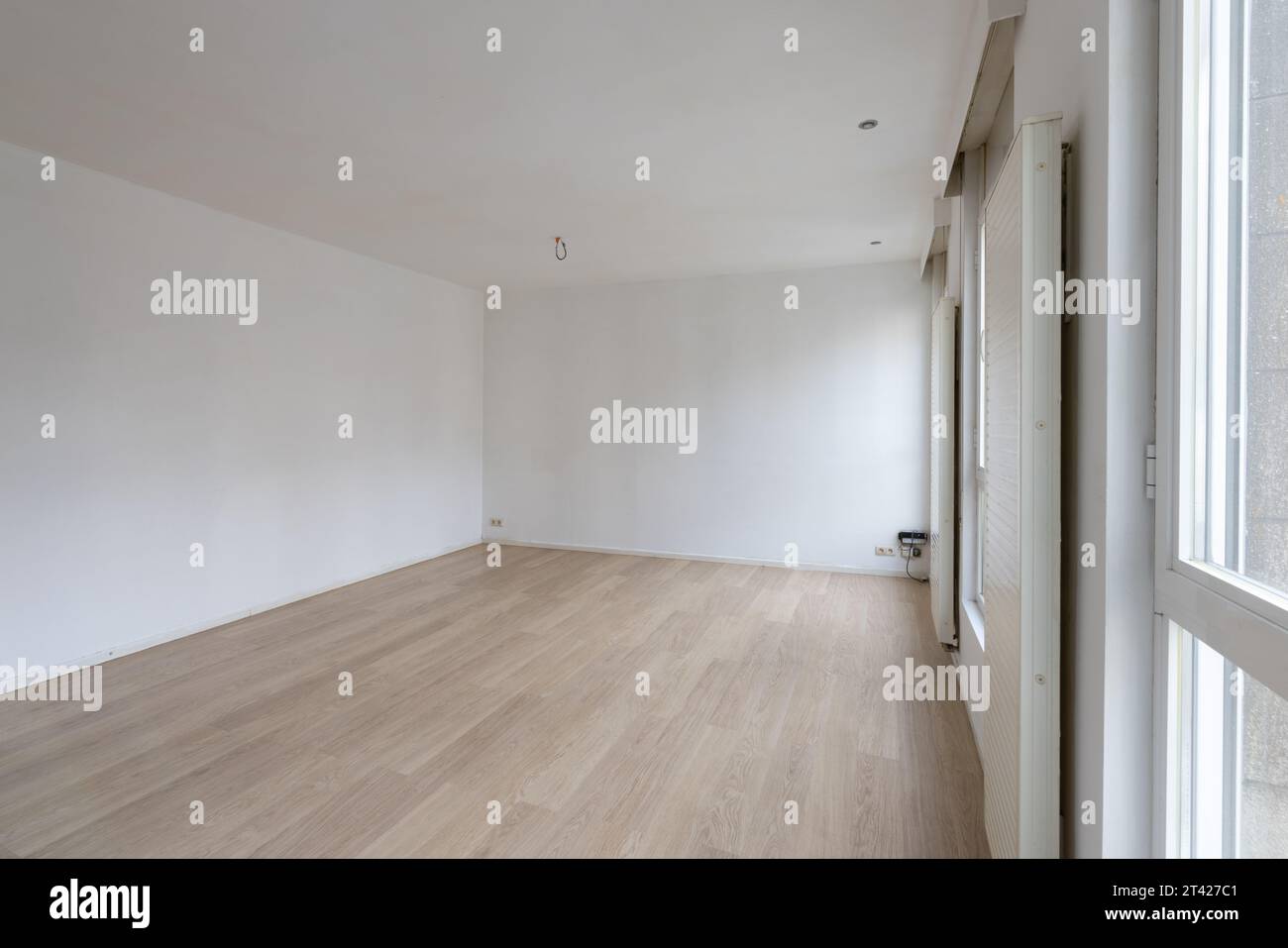Uno spazio interno con pavimenti in legno duro e pareti bianche Foto Stock