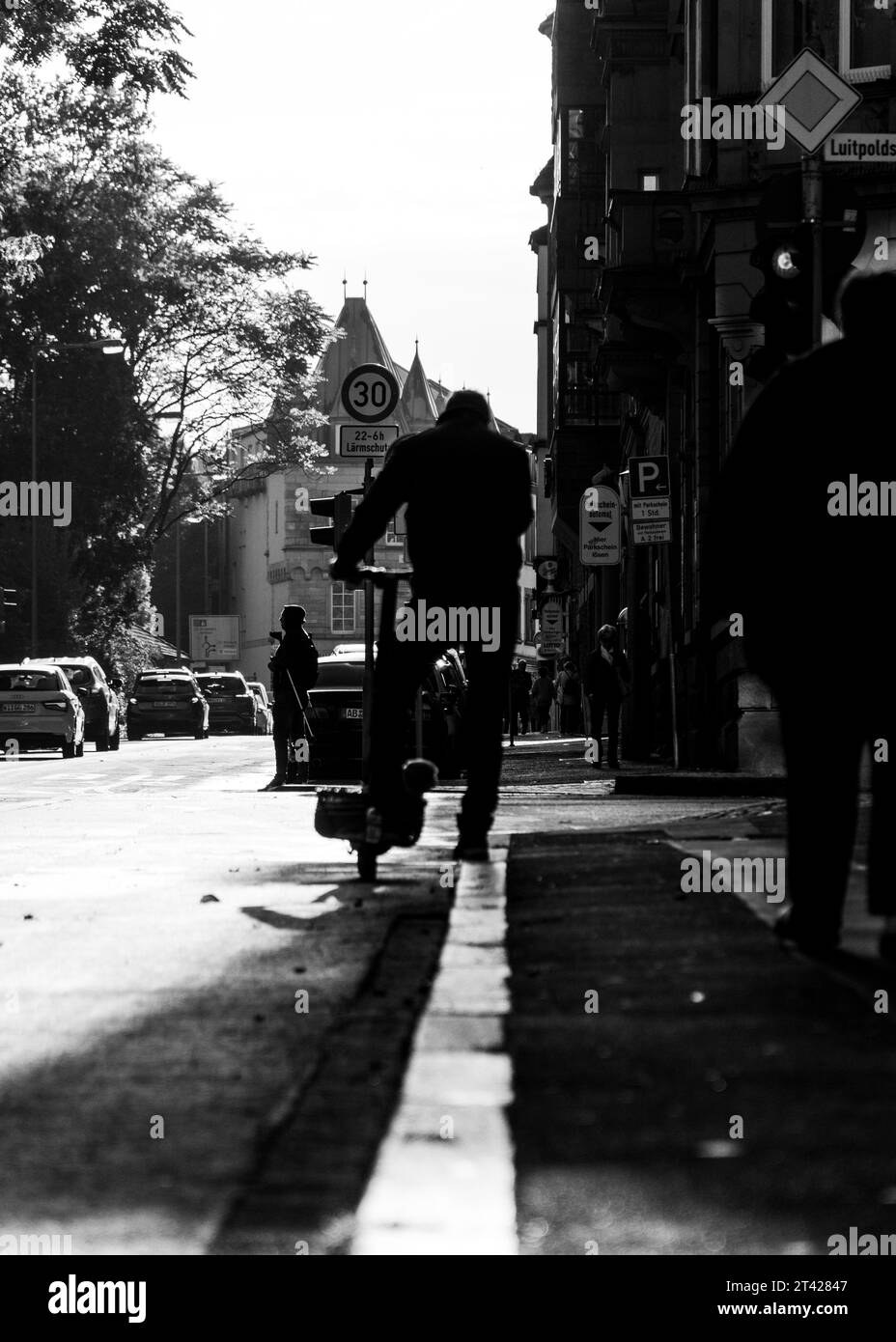 Una fotografia in bianco e nero di un uomo che guida uno scooter in un ambiente urbano Foto Stock