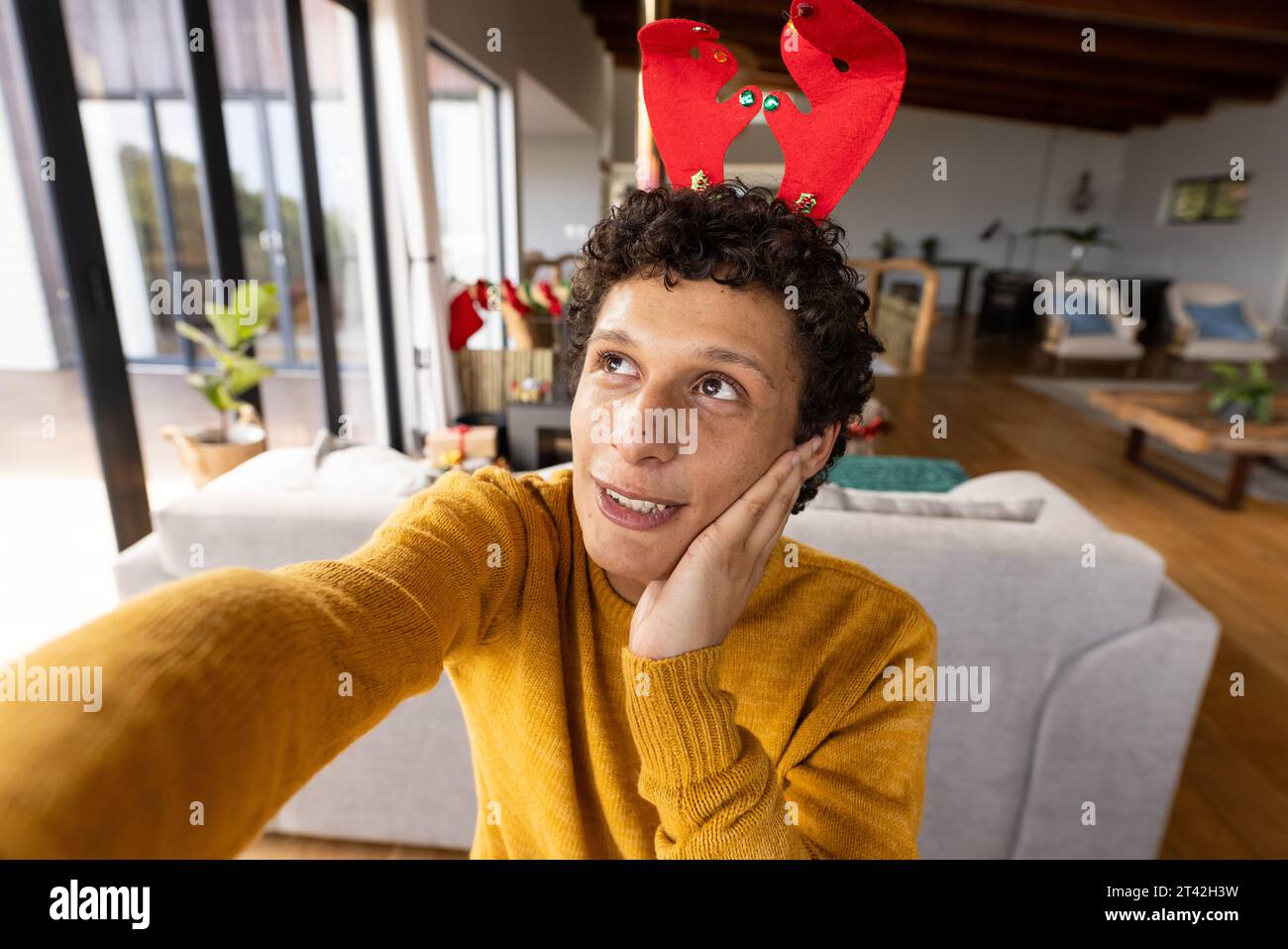 Ritratto di un felice uomo birazziale che indossa le corna delle renne e  che guarda un video a natale a casa Foto stock - Alamy