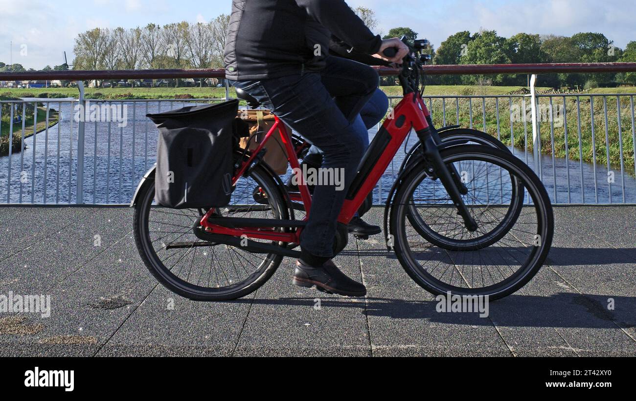 Due ciclisti cavalcano su un ponte sul fiume Vecht in una zona rurale nei Paesi Bassi Foto Stock