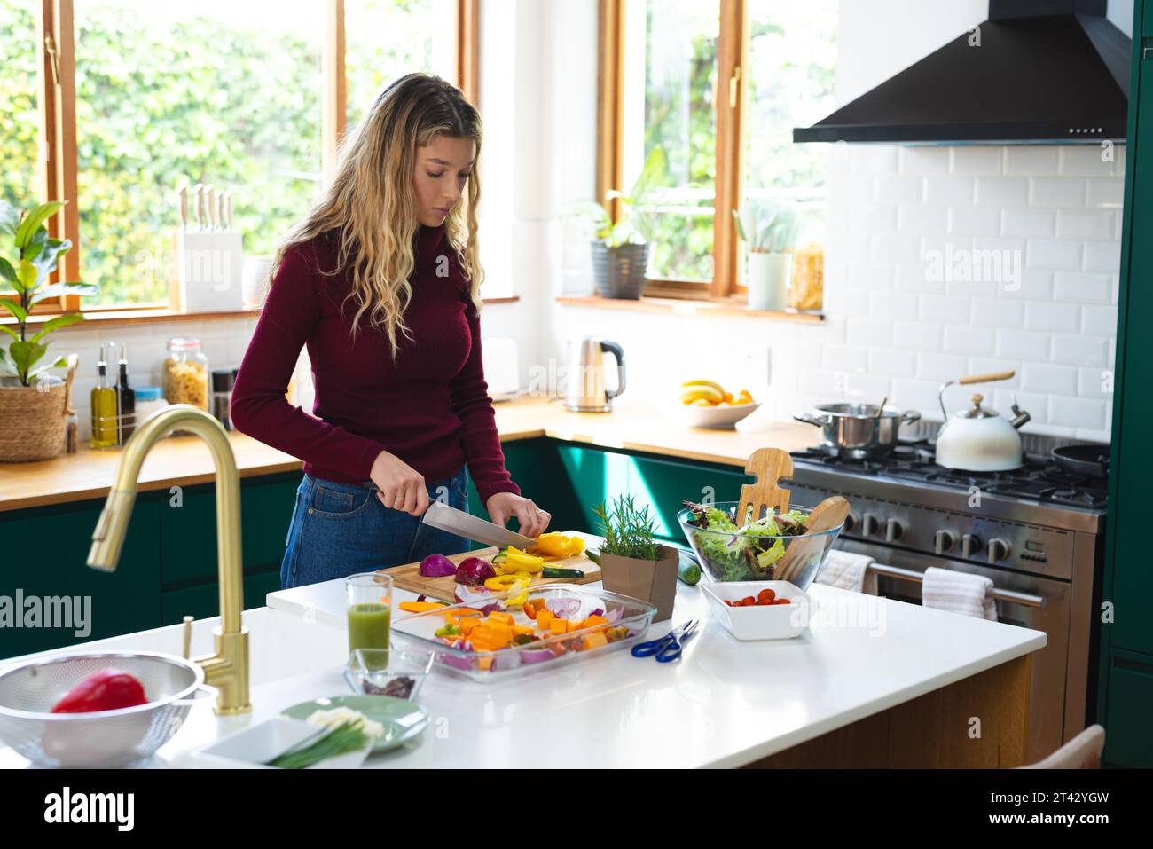 Donna caucasica concentrata che prepara il cibo, trita le verdure in cucina, spazio copia Foto Stock