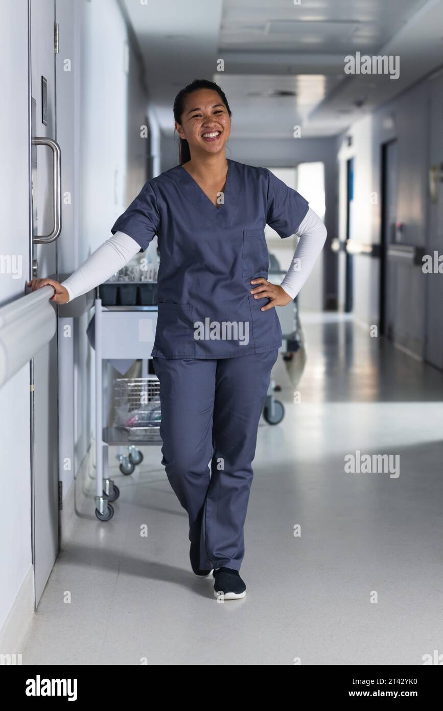 Ritratto di felice medico asiatico femminile che indossa scrub in ospedale Foto Stock