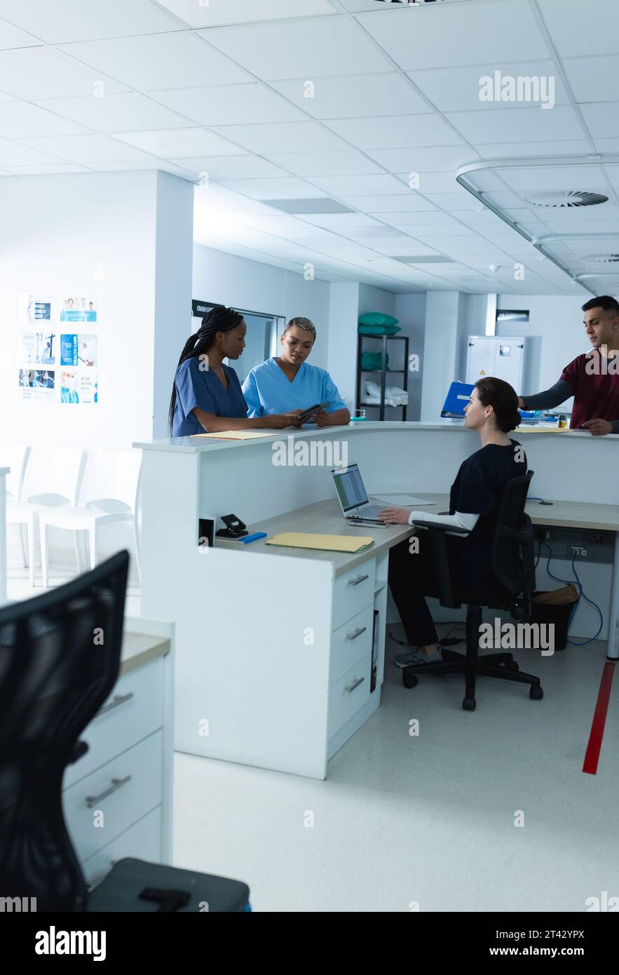 Diverse medici donne che discutono di lavoro, utilizzando tablet alla reception in ospedale Foto Stock