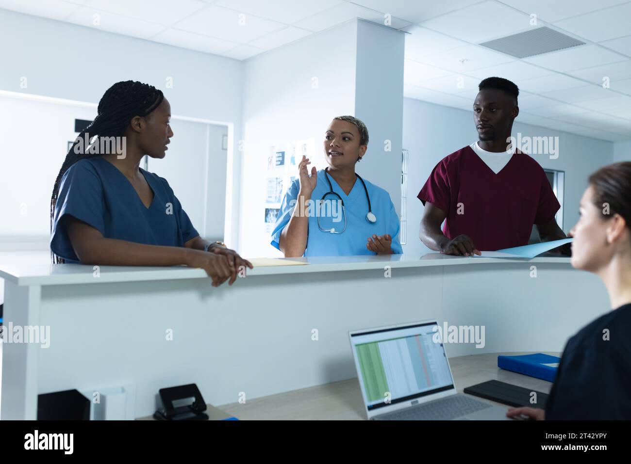 Diversi medici maschili e femminili discutono di lavoro alla reception dell'ospedale Foto Stock