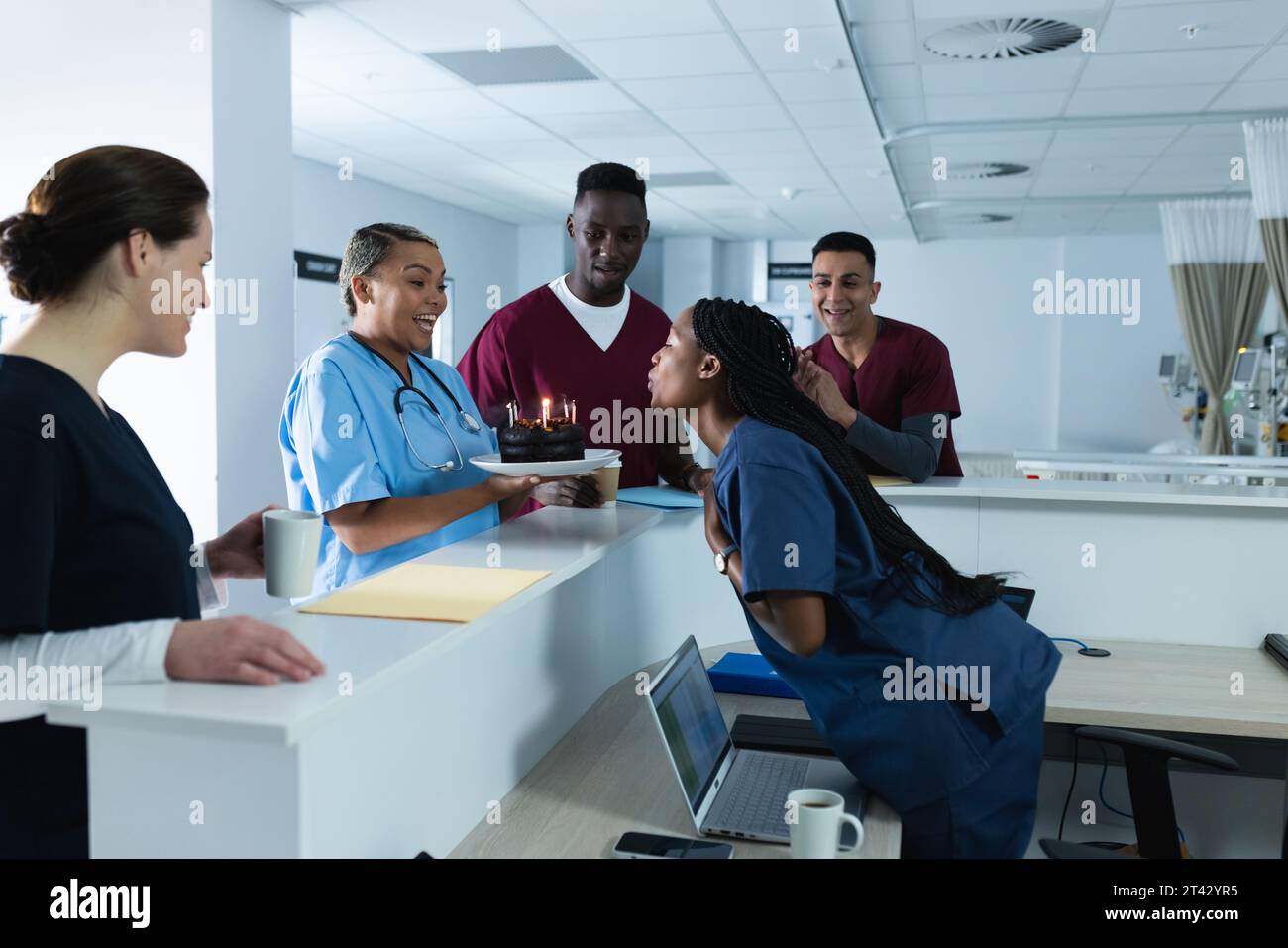 Felici diversi medici maschi e femmine che celebrano il compleanno alla reception in ospedale Foto Stock