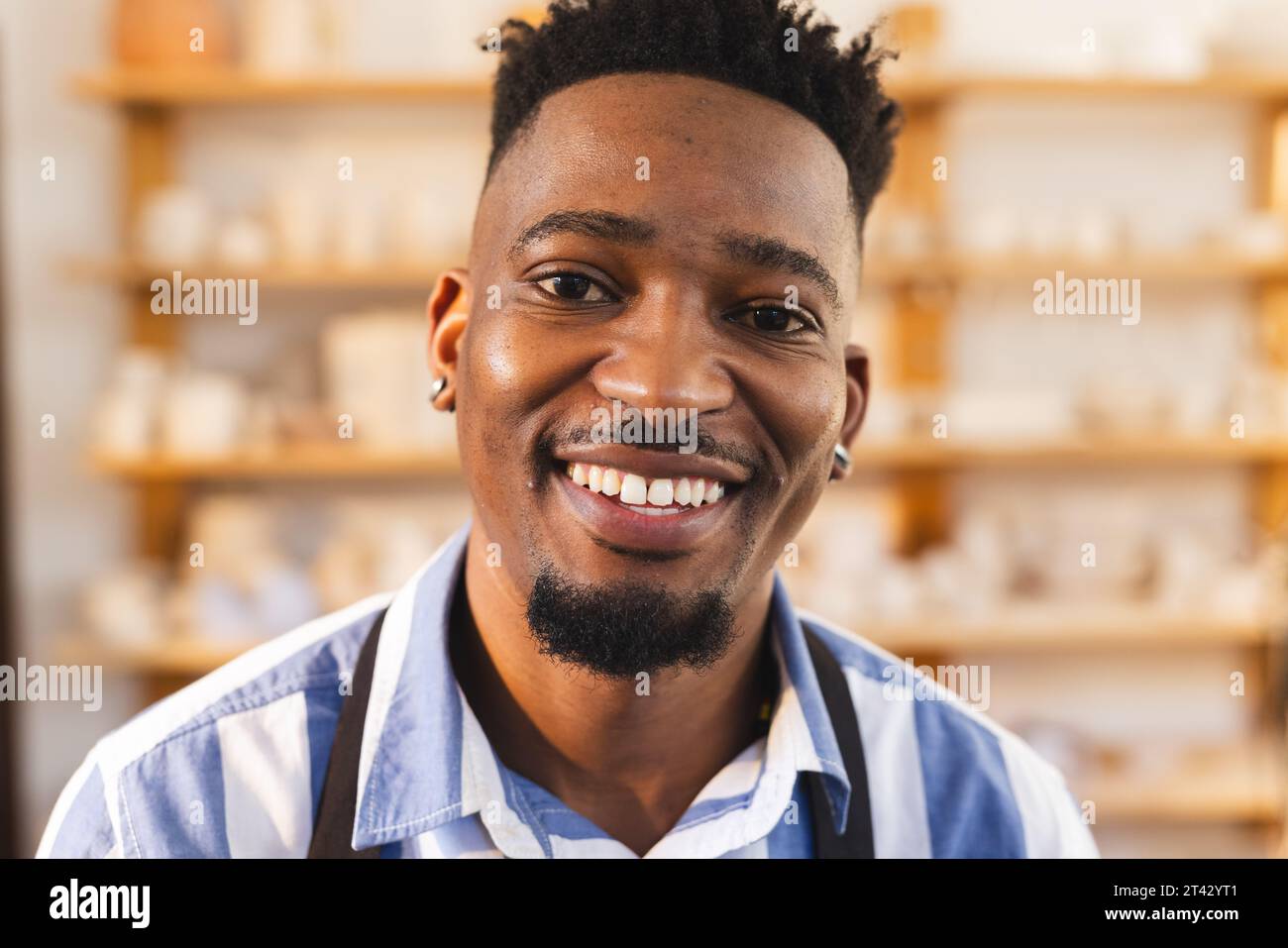 Buon ceramista afroamericano che guarda la macchina fotografica e sorride nello studio di ceramica Foto Stock