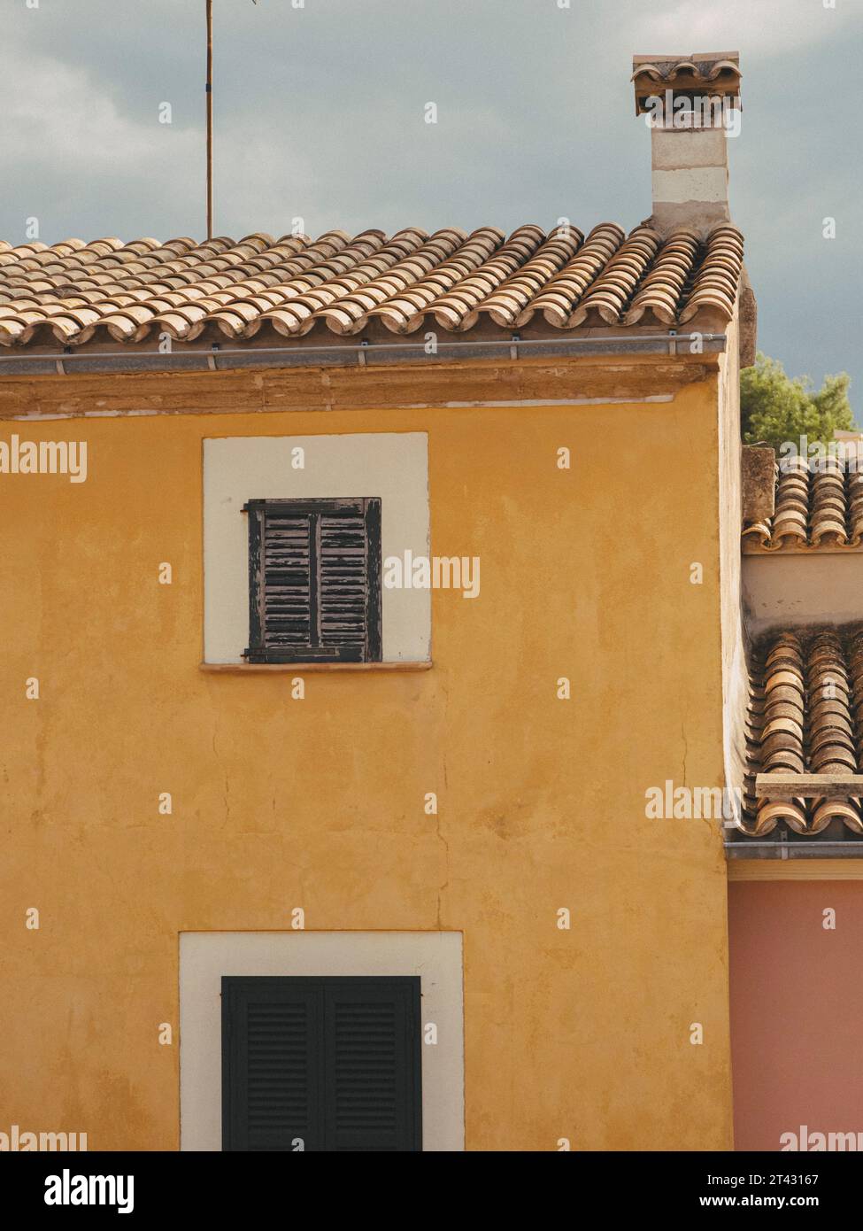 Fotografia di una rustica casa mediterranea gialla con persiane verdi Foto Stock