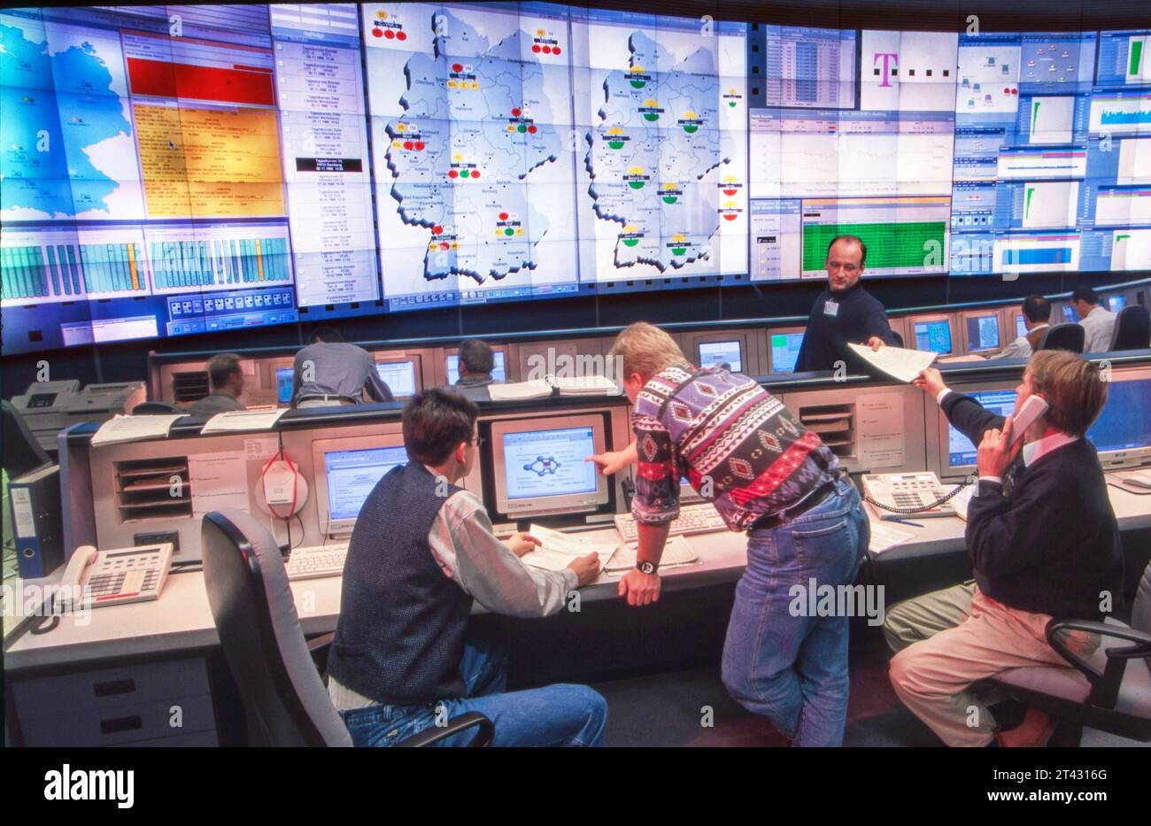 Deutsche Telekom, Network-Management-Center Bamberg, 1998 Deutschland, Bamberga, 01.12.1998, Kommunikationszentrale Deutsche Telekom, das heutige Network-Management-Center, Netzmanagement Center, das NMC Bamberg wurde 1997 gegründet, zur Steuerung und Überwachung des bundesweiten Telefonnetzes, Kundenservice, Technik, Schaltzentrale, Netzwerkzentrale, Netz, Kontrollraum, Leitstand, Leitwarte, Leitstelle, Telekom-Mitarbeiter kontrollieren Netz, versuchen Störfälle, Störungen, Leitungsstörungen, Technik-Ausfall, Netz-Probleme schnell zu beheben, Internet, Mobilfunk, Command Center, Mitarbeiter, M Foto Stock