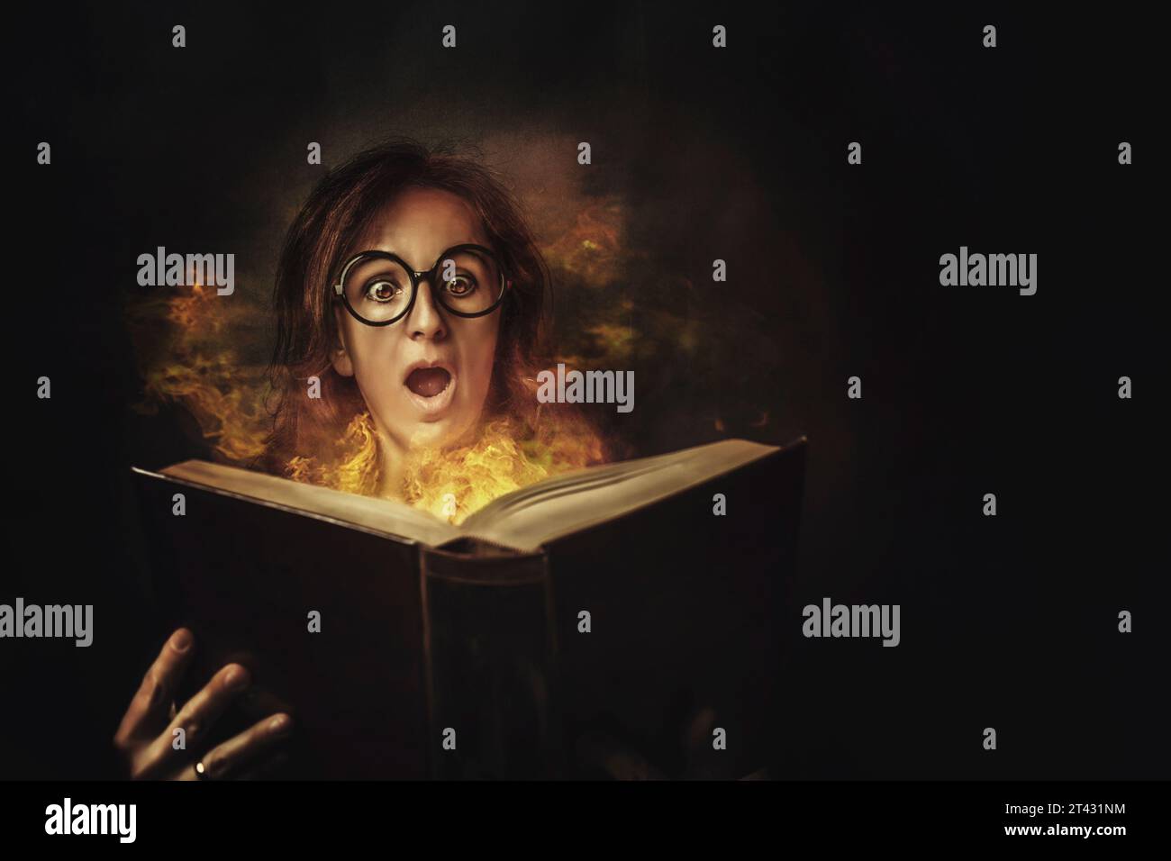 Ritratto di una donna spaventata che apre un libro con pagine in fiamme Foto Stock