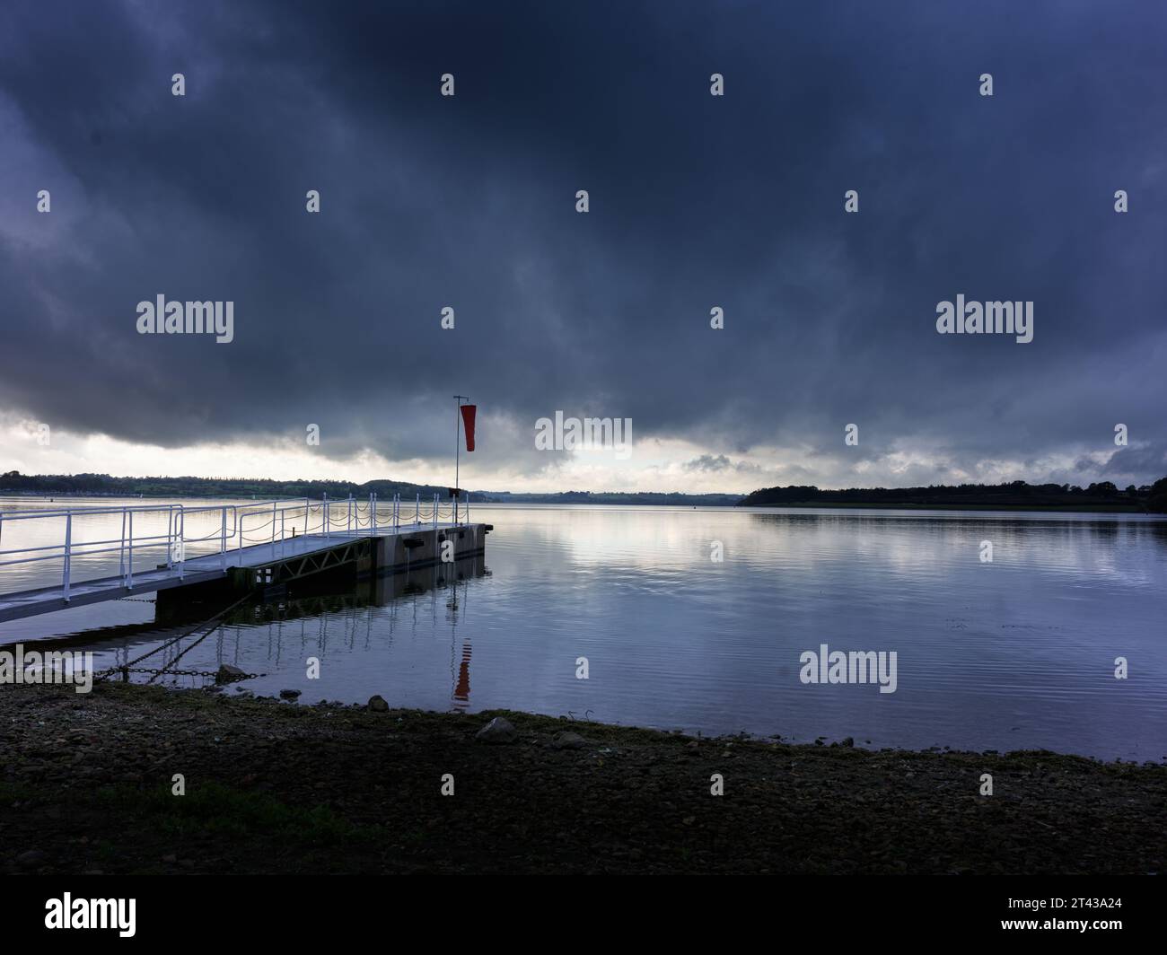 Nuvola chiara e scura su un molo in riva al lago in una giornata tranquilla. Foto Stock