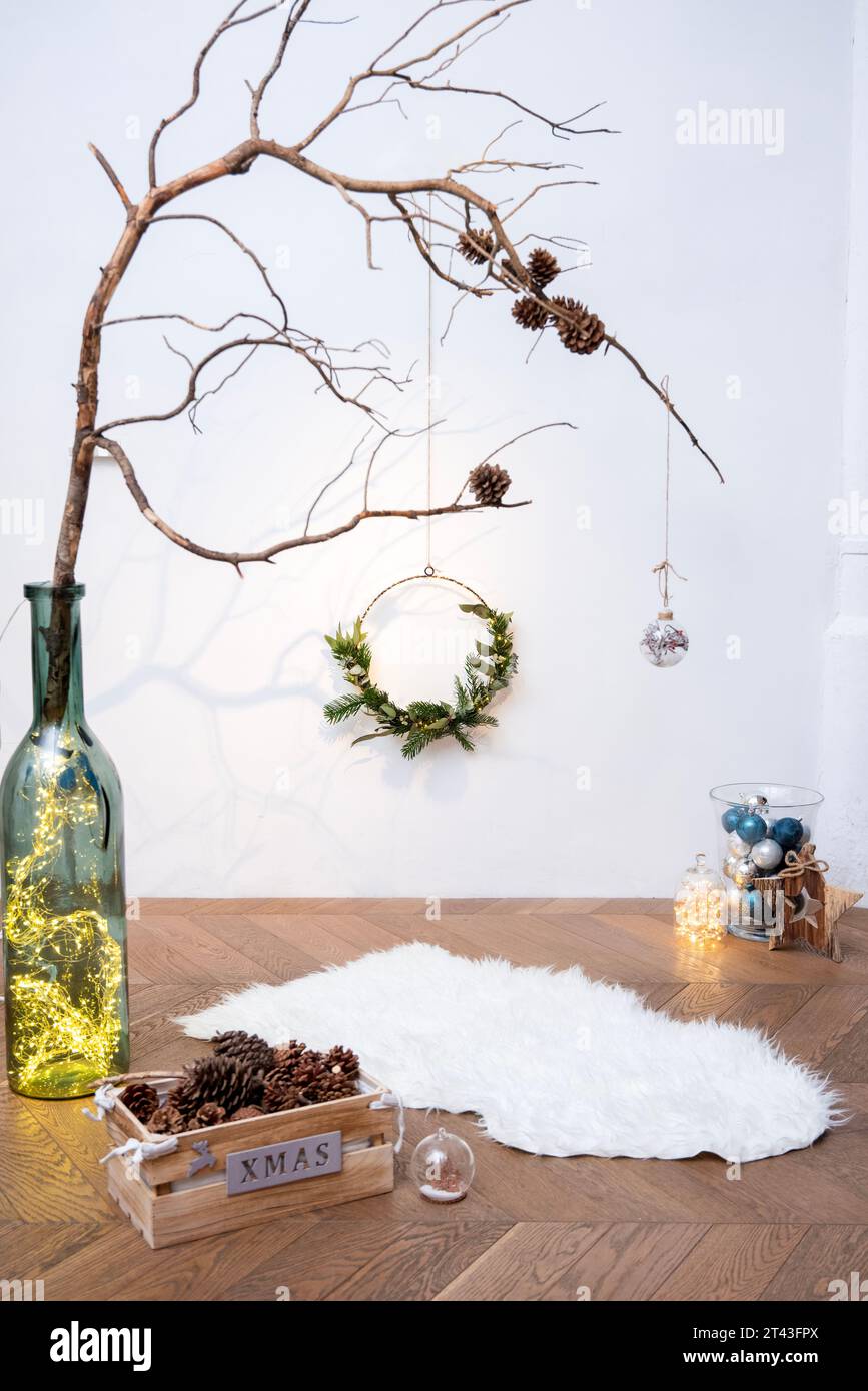 Cattura l'incanto della stagione natalizia in un allestimento da studio, con ornamenti, luci e un rustico ramo ornato di pinecone. Foto Stock