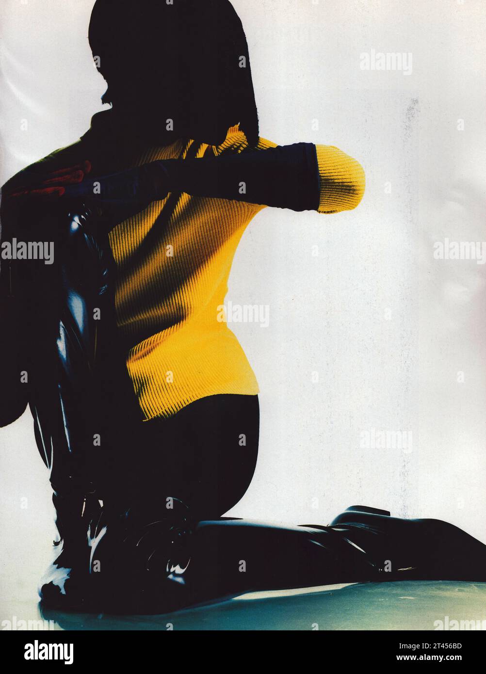 Fotografia vintage alla moda, donna seduta sul pavimento con giacca gialla di Michael Klein e maglione giallo e calze Wolford nere Foto Stock