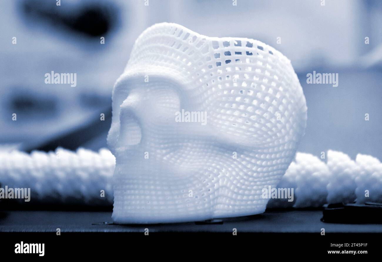 Piccolo prototipo di cranio umano stampato in 3D da plastica bianca fusa in primo piano sulla superficie. Modello tridimensionale. Tecnologia medica additiva progressiva. Nuova e moderna industria di produzione della stampa. Foto Stock