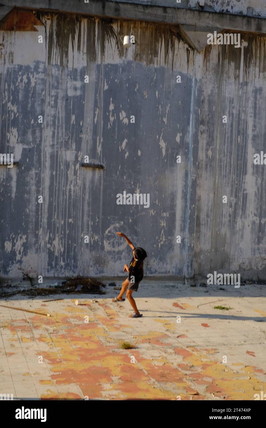 Bambino singolo in piedi accanto a un muro di cemento in una struttura architettonica Foto Stock