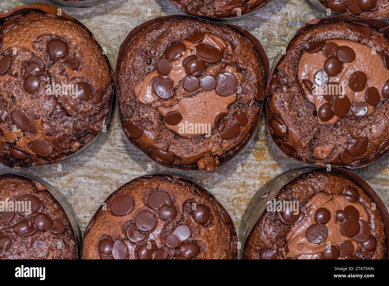 Muffin fatti in casa con gocce di cioccolato sparse e panna montata, flash macro-fotografico estremamente ravvicinato sopra la vista. Foto Stock