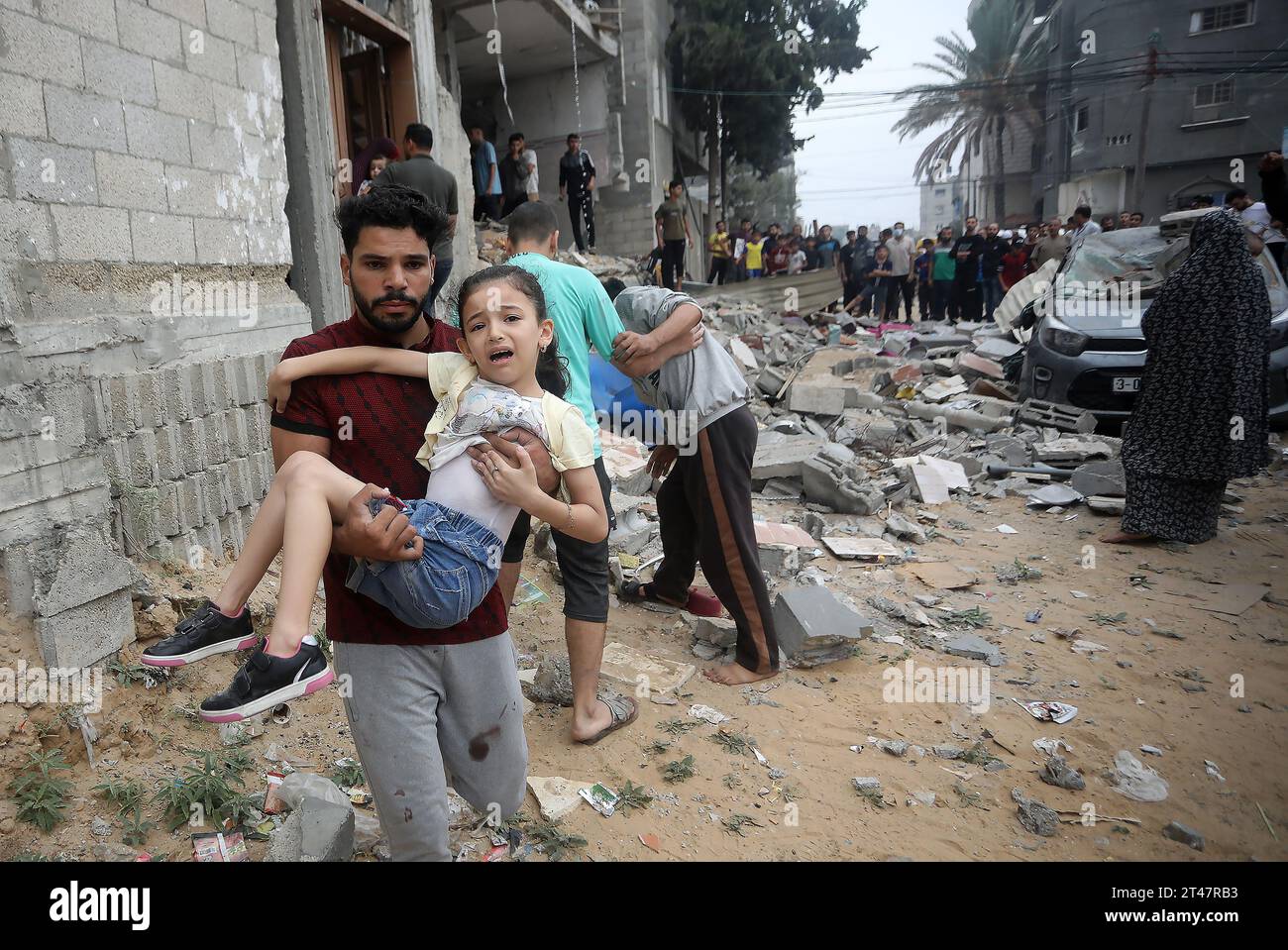 Rafah, Gaza. 28 ottobre 2023. Un uomo palestinese trasporta agirl in seguito ai bombardamenti israeliani sulle case della famiglia AL-Mgary a Rafah, nella Striscia di Gaza meridionale, domenica 29 ottobre 2023. Israele ha attaccato Gaza con altri attacchi aerei e terrestri il 29 ottobre in una campagna militare in aumento, in quanto l'ONU ha avvertito che l'ordine civile stava "cominciando a crollare” nel territorio palestinese assediato. Foto di Ismael Mohamad/UPI. Crediti: UPI/Alamy Live News Foto Stock