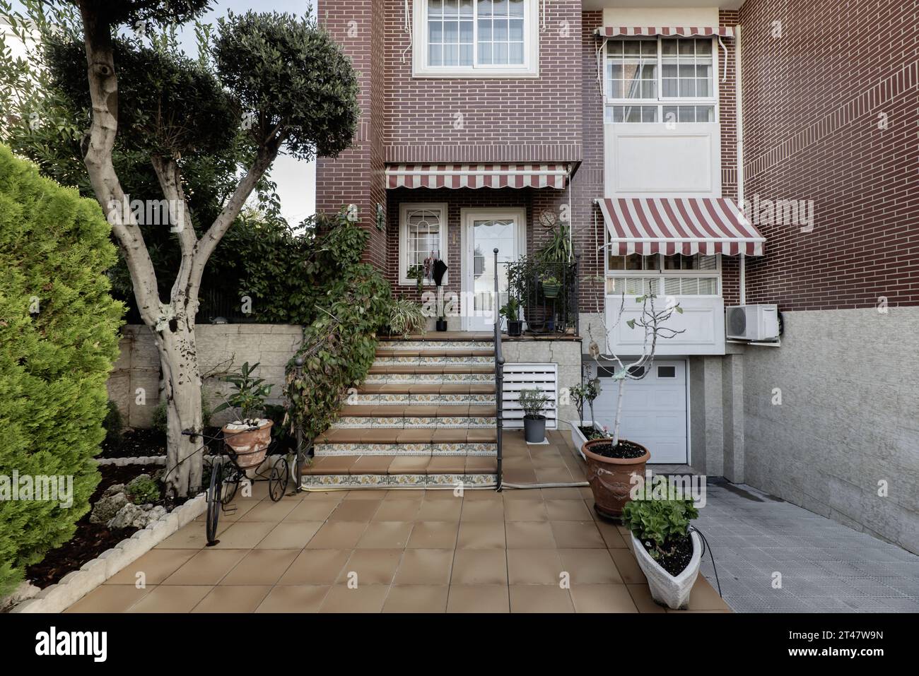 Immagine frontale della facciata di una casa unifamiliare con scale che conducono al portico, una rampa verso il garage Foto Stock