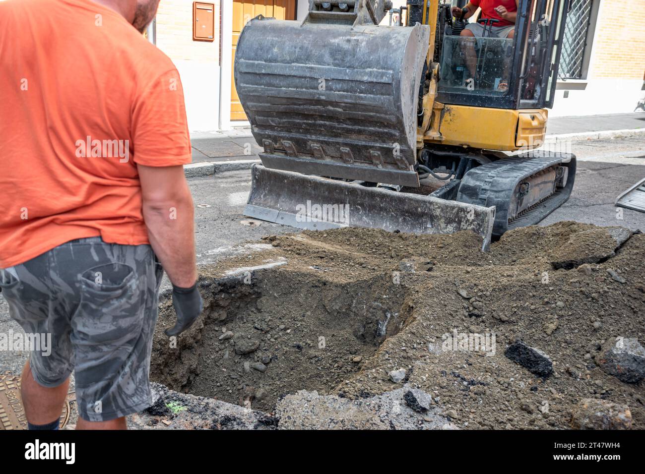 Operatore che supervisiona l'escavatore durante lo scavo nell'area di costruzione Foto Stock