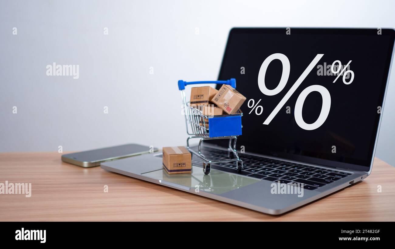 Percentuale di vendita con carrello e scatole posizionati sulla tastiera del computer. Concetto di shopping online, prodotti a prezzo speciale, offerte speciali e promozioni Foto Stock