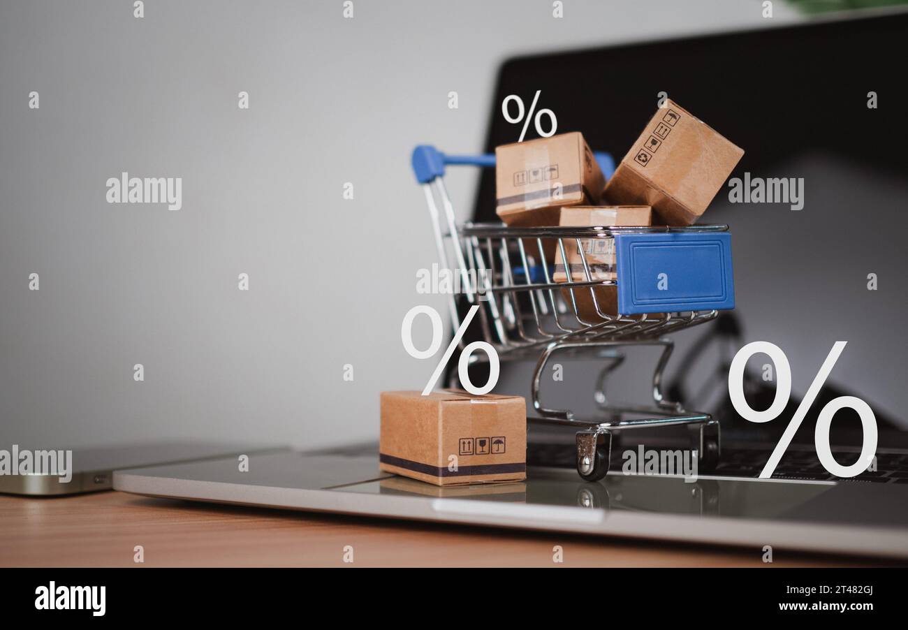 Percentuale di vendita con carrello e scatole posizionati sulla tastiera del computer. Concetto di shopping online, prodotti a prezzo speciale, offerte speciali e promozioni Foto Stock
