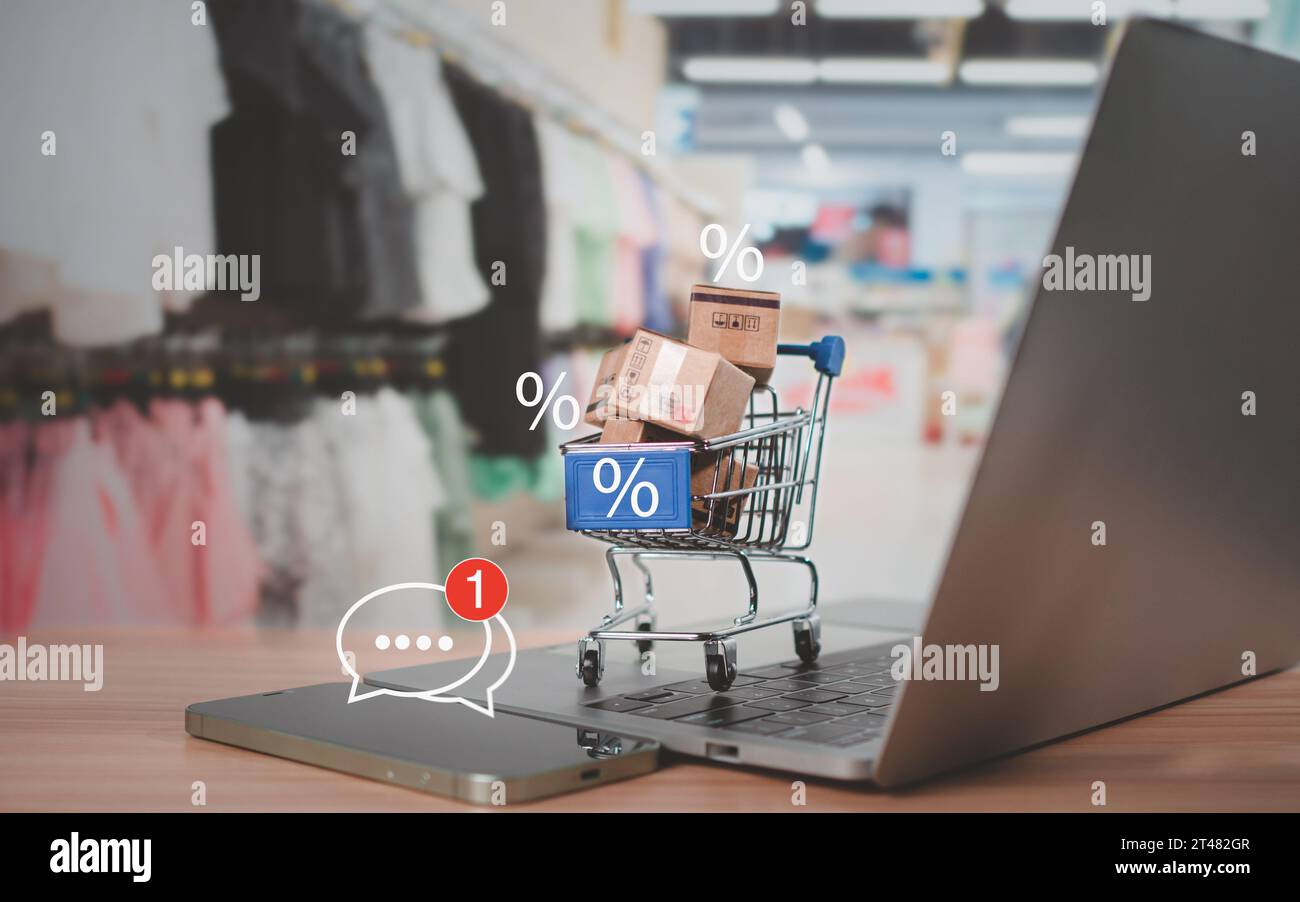 Percentuale di vendita con carrello e scatole posizionati sulla tastiera del computer. Concetto di shopping online, prodotti a prezzo speciale, offerte speciali e promozioni Foto Stock
