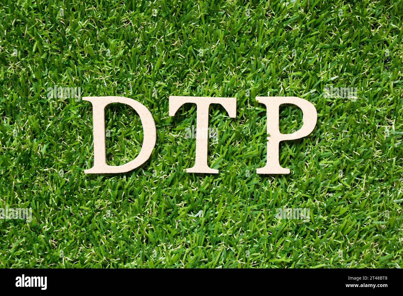 Lettera alfabetica di legno in parola DTP (abbreviazione di Delivered at Terminal Paid, desktop publishing, Direct to patient) su erba verde artificiale backgro Foto Stock