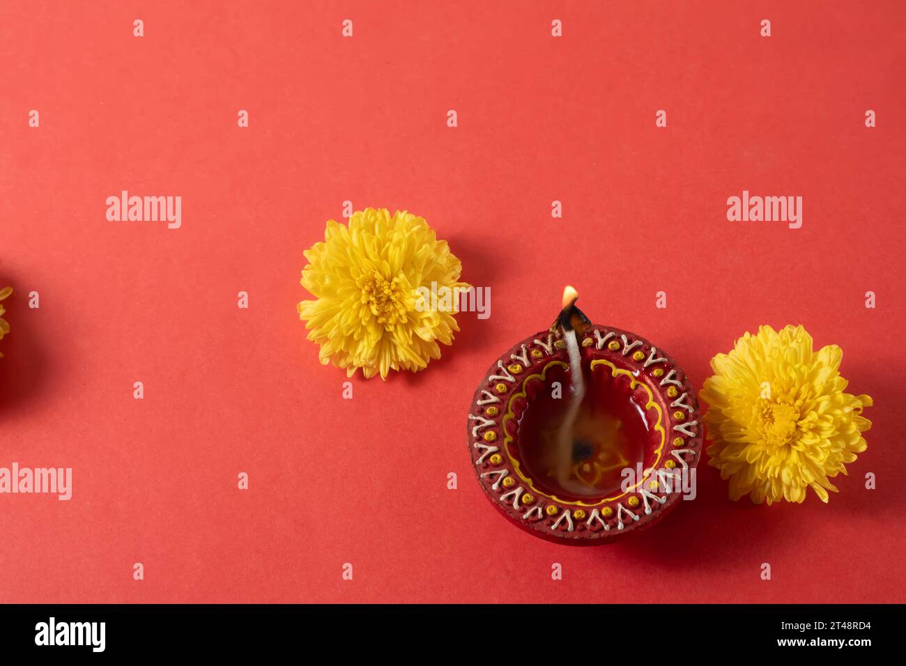 Auguri per il festival Happy Diwali e Kartika Deepam - colorata argilla Deepam con fiori gialli su sfondo rosso Foto Stock