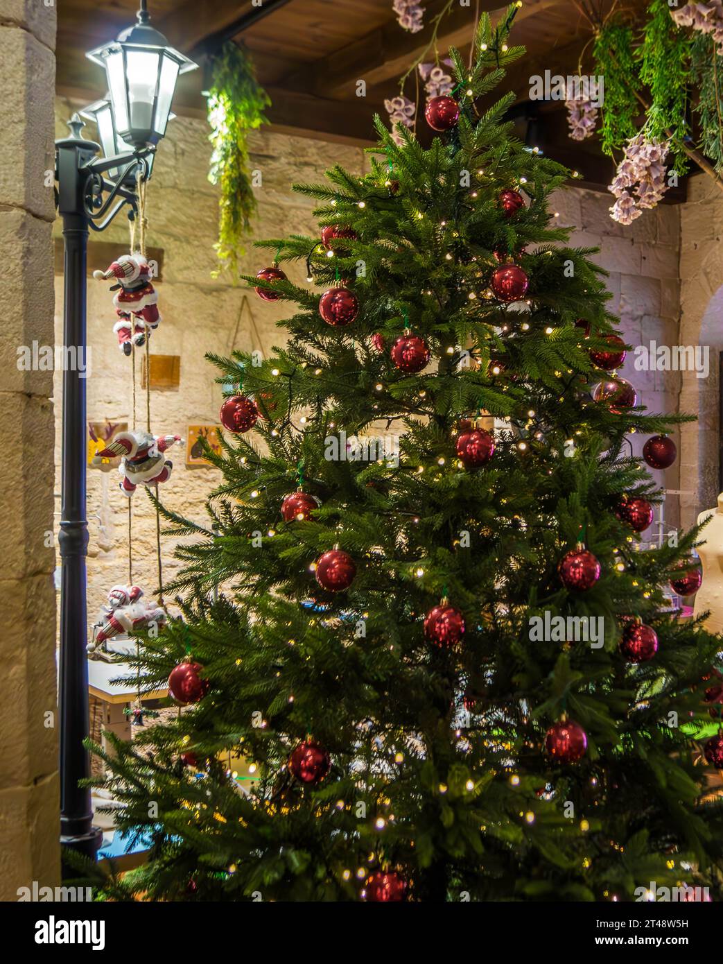 L'albero di Natale verde con le palle rosse e le luci blu sopra. Foto Stock